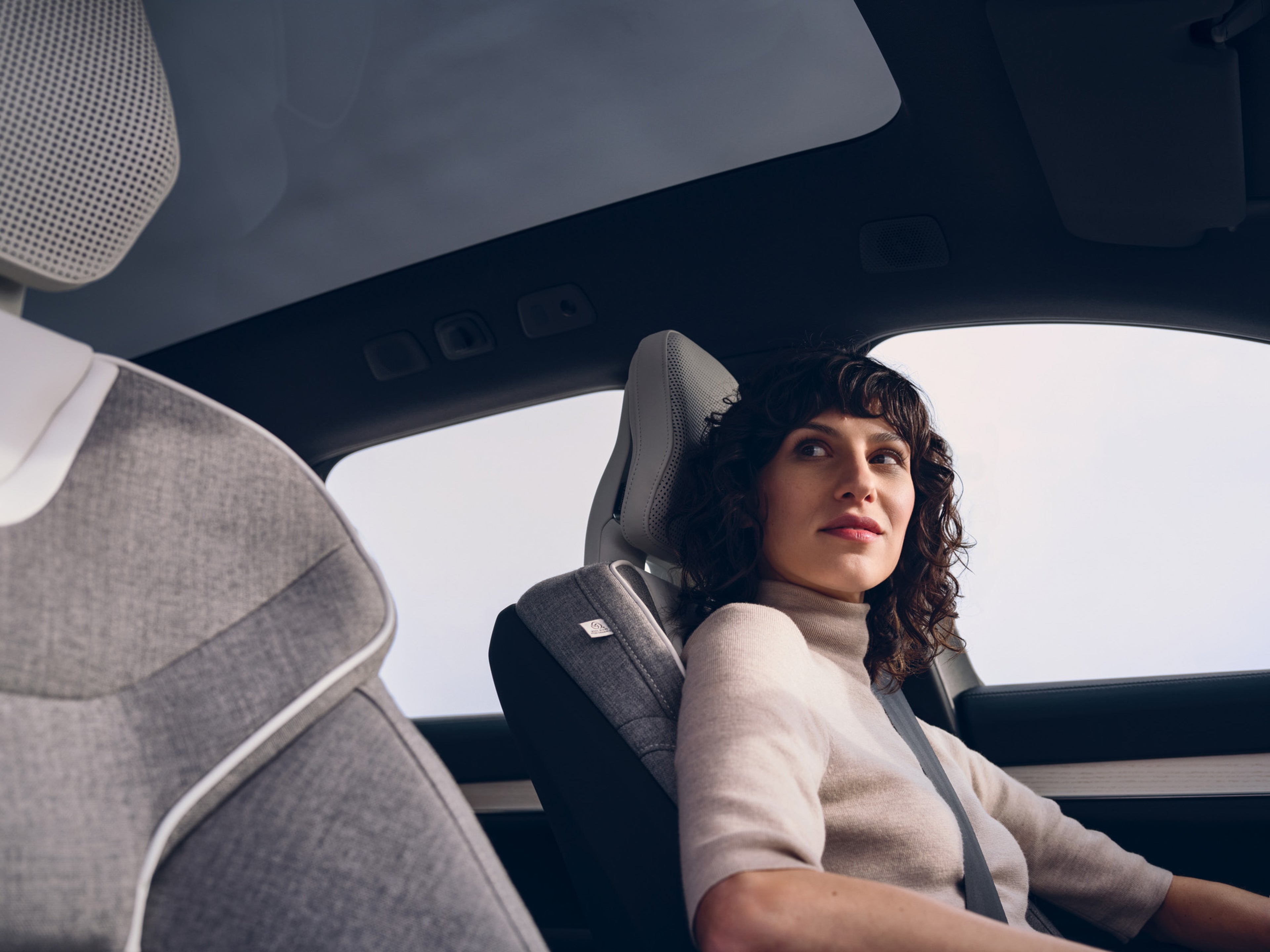 A woman sitting in a Volvo Cars driver’s seat looking to the side.