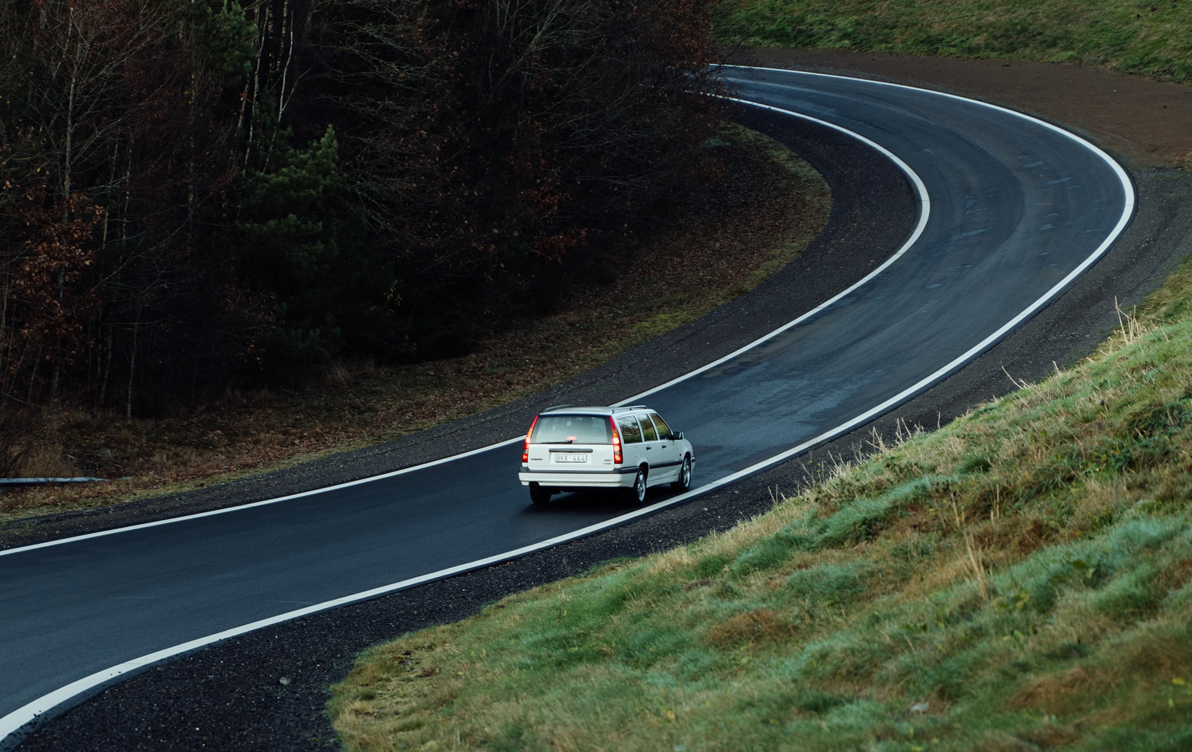 A Volvo 850 wagon driving on a winding forest road.