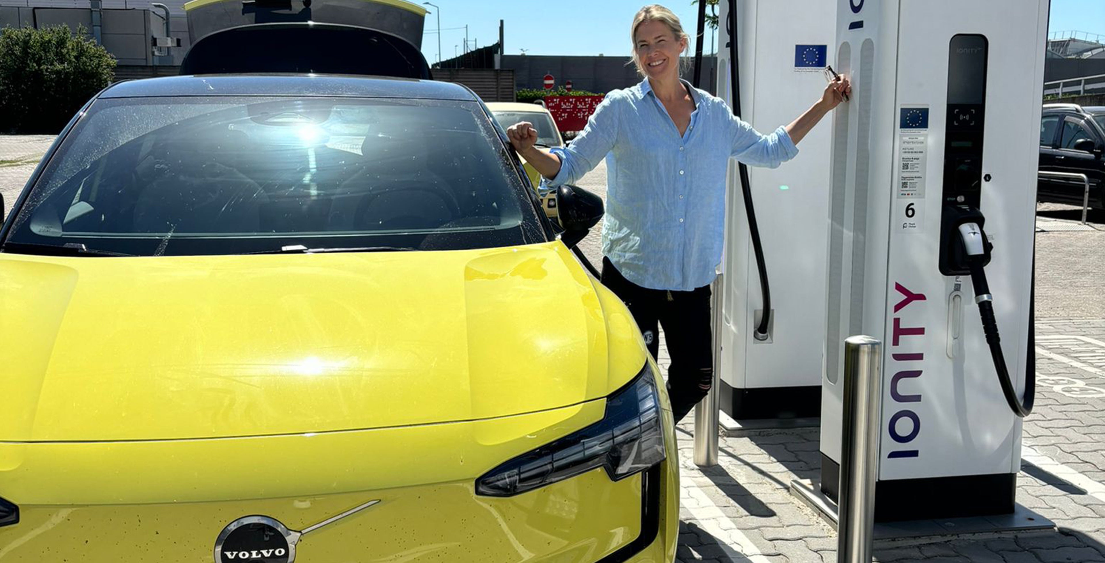 Ella Kanninen lataamassa Moss Yellow -väristä Volvo EX30 täyssähköautoa.
