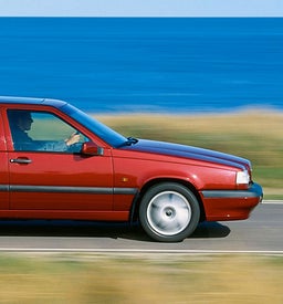 رجل يقود Volvo 850 سيدان حمراء.
