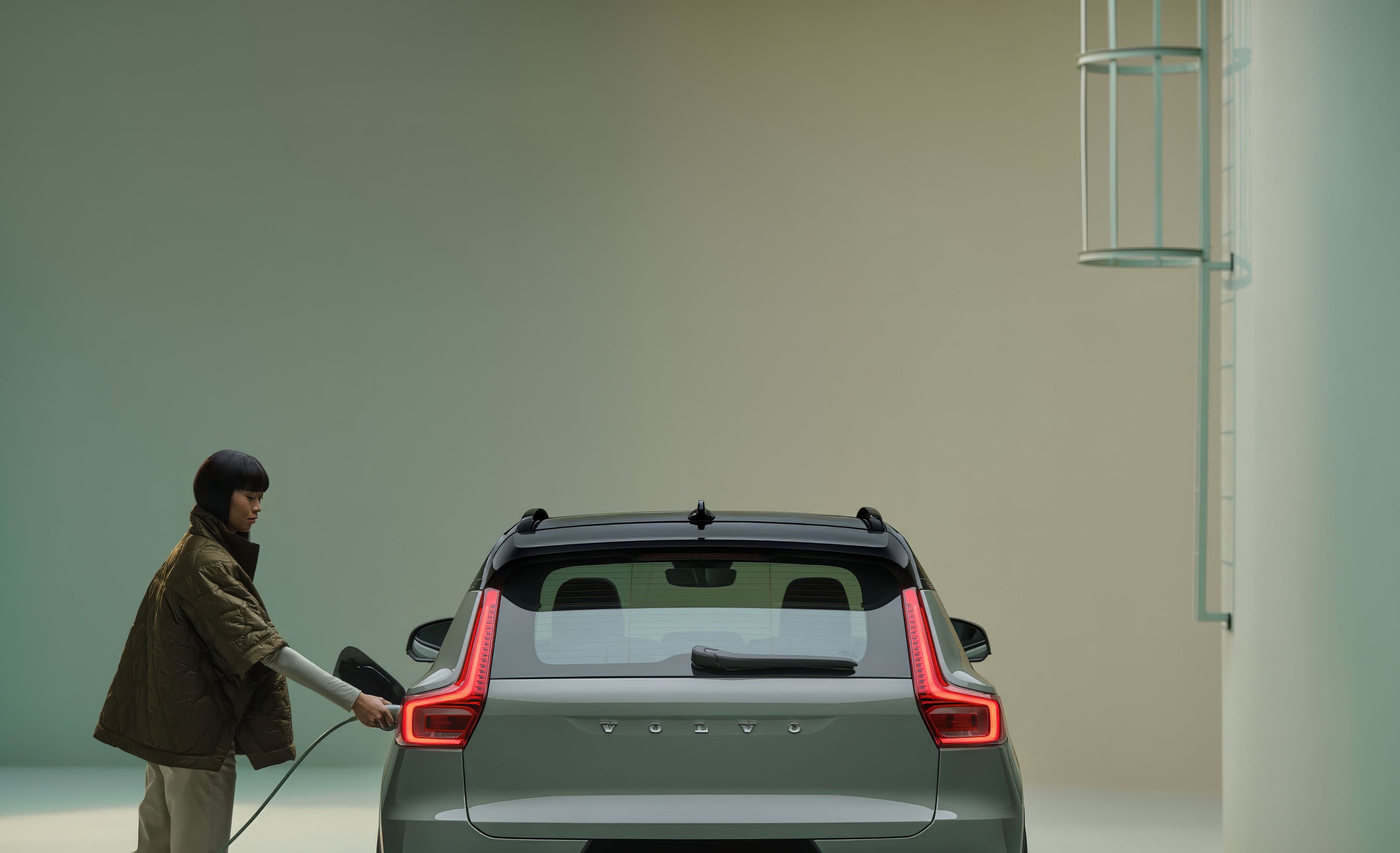 žena pripájajúca nabíjací kábel pri stojacom aute