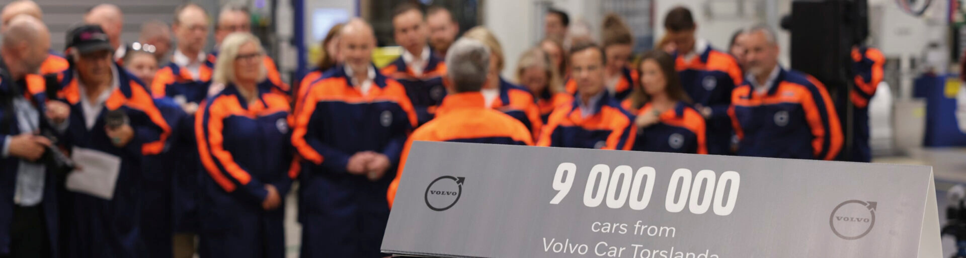 Mitarbeiter des Volvo Werks in Torslada stehen vor einem Schild mit Aufschrift 9 Millionen Autos in Torslada
