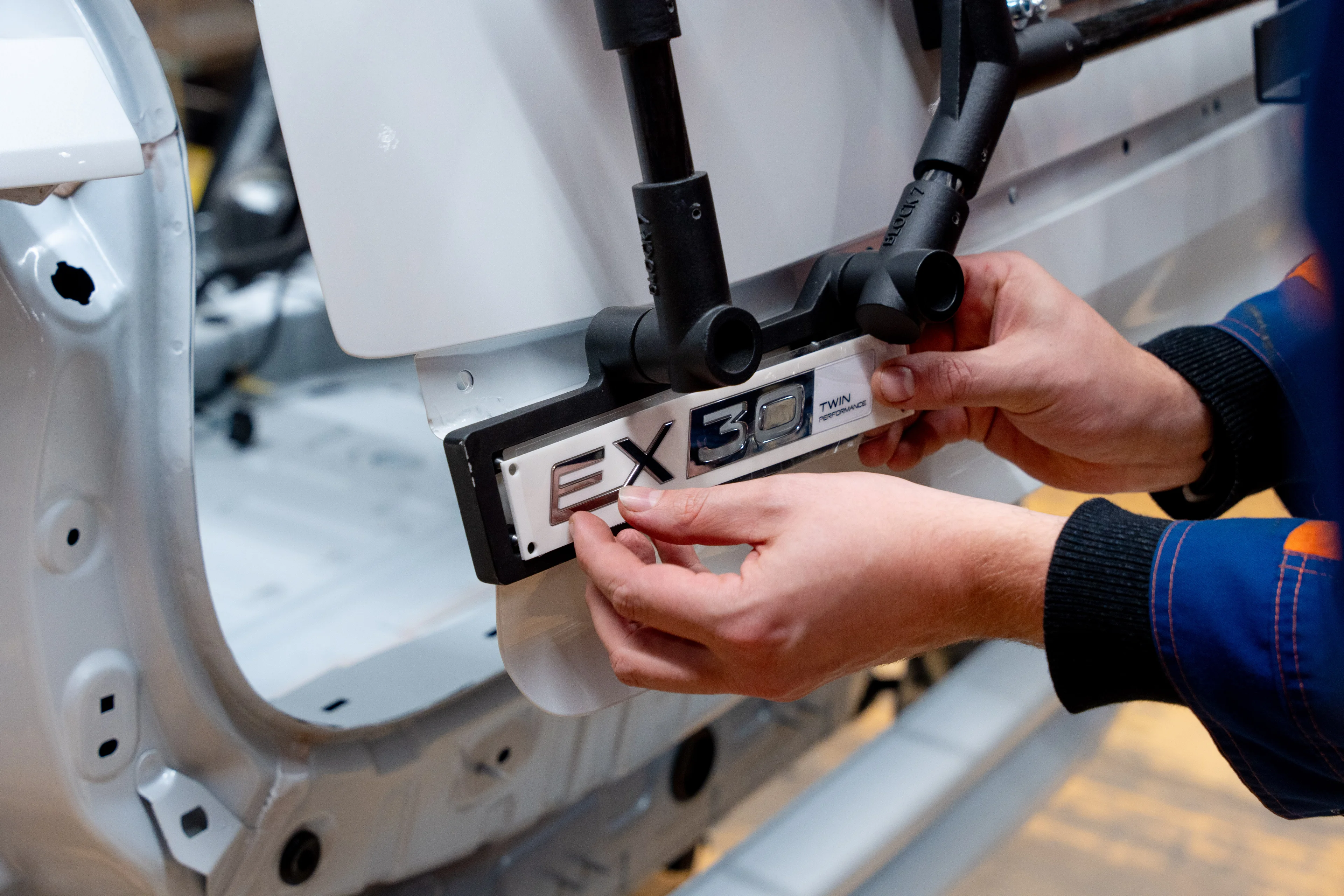 Technician applies EX30 Twin Performance badge during Volvo EX30 production start at Ghent plant.
