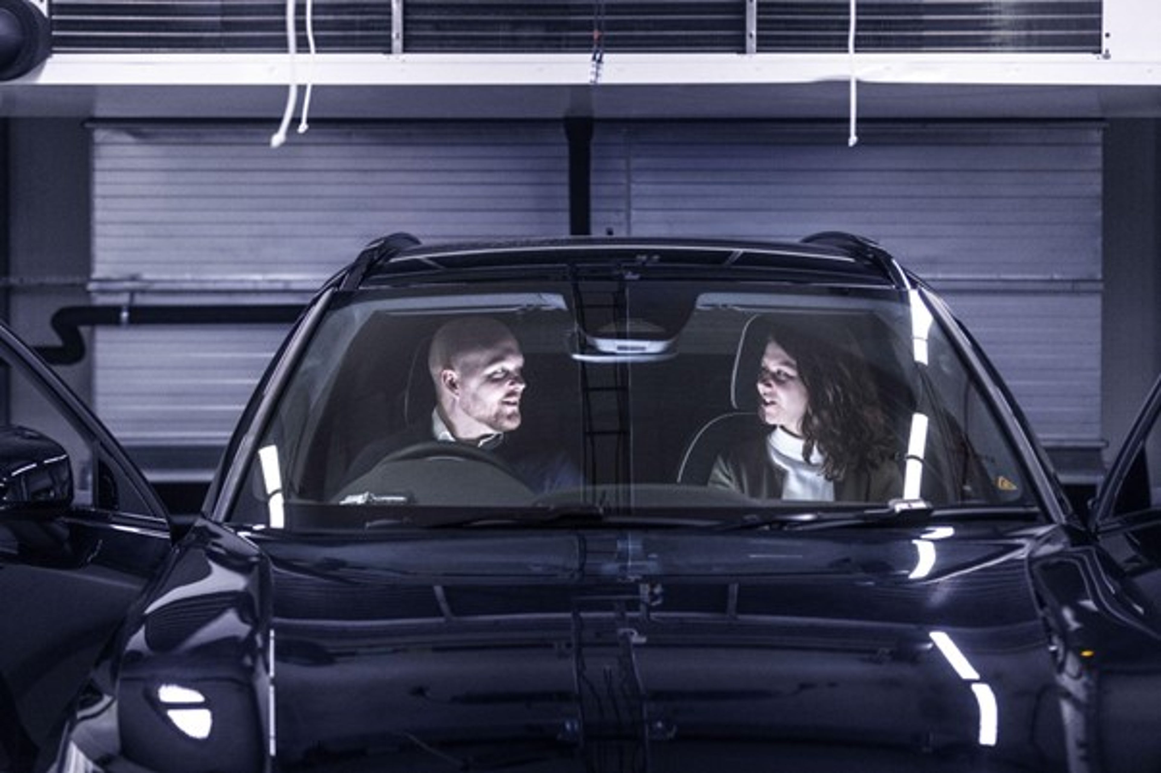 A man and a woman looking at each other from the inside of a Volvo.