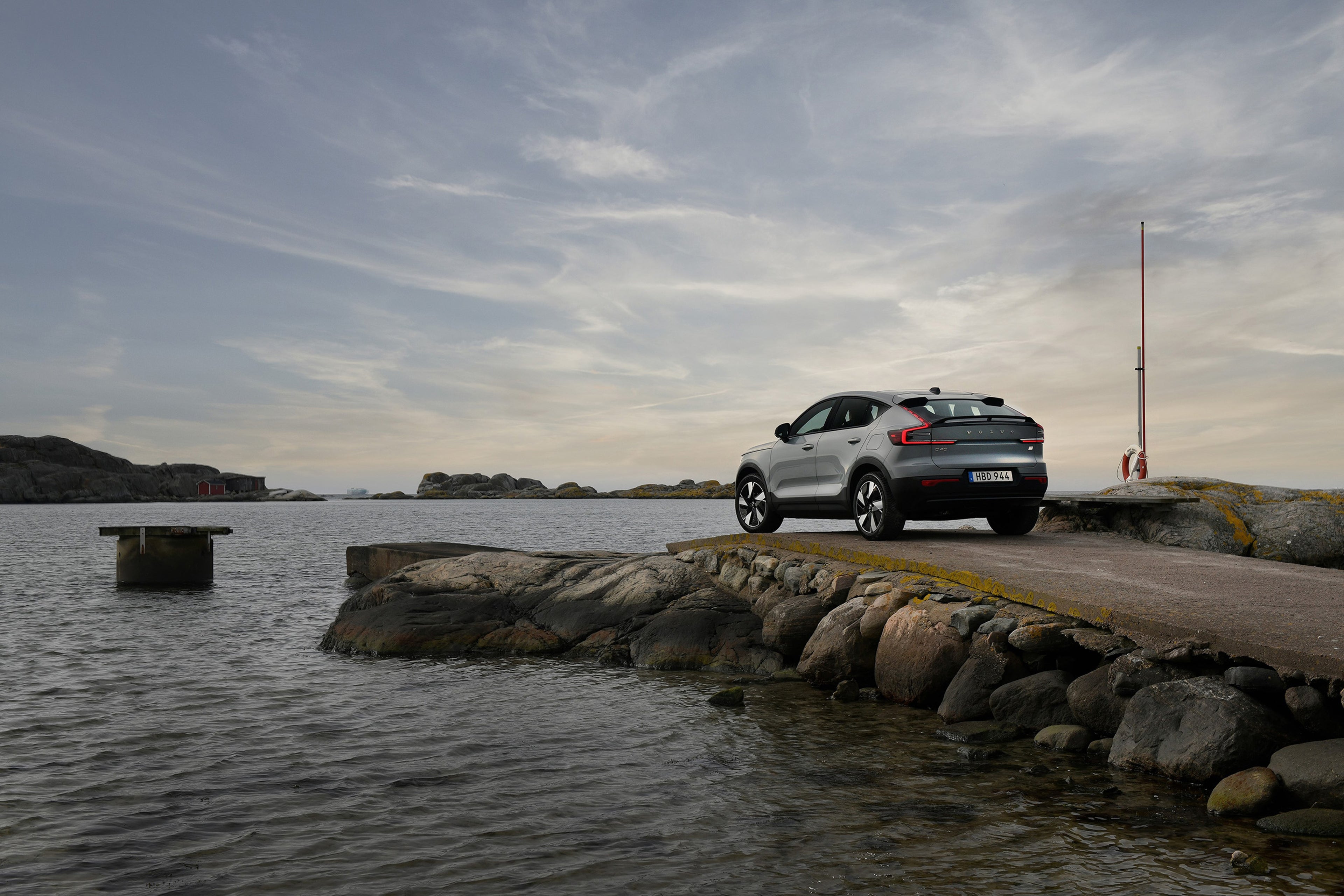 Electric Volvo EC40 car parked on a pier by the sea at sunset.
