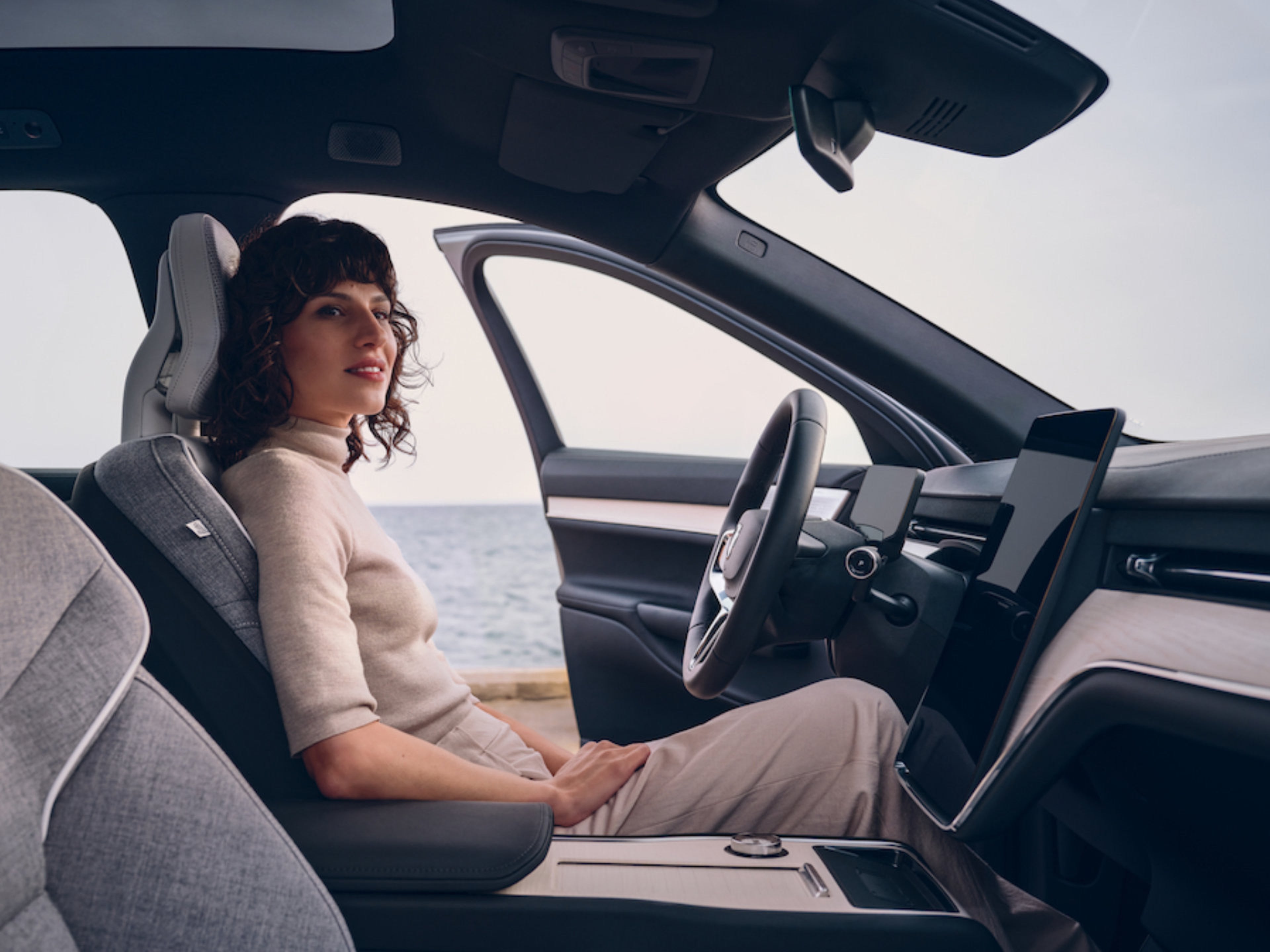 Eine braunehaarige Frau sitzt am Steuer eines Volvo EX90 und schaut hinaus.