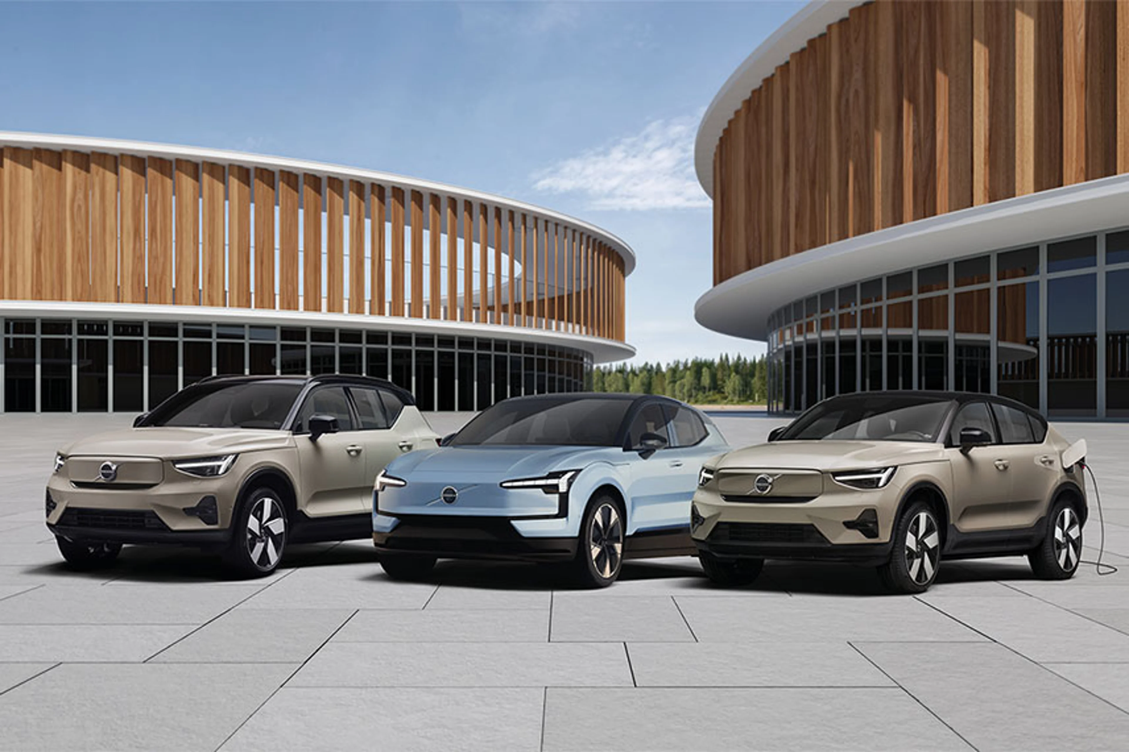 Gamme Volvo électrique : trois modèles inspirants devant une architecture en bois moderne, alliance parfaite entre nature, design et avenir durable.