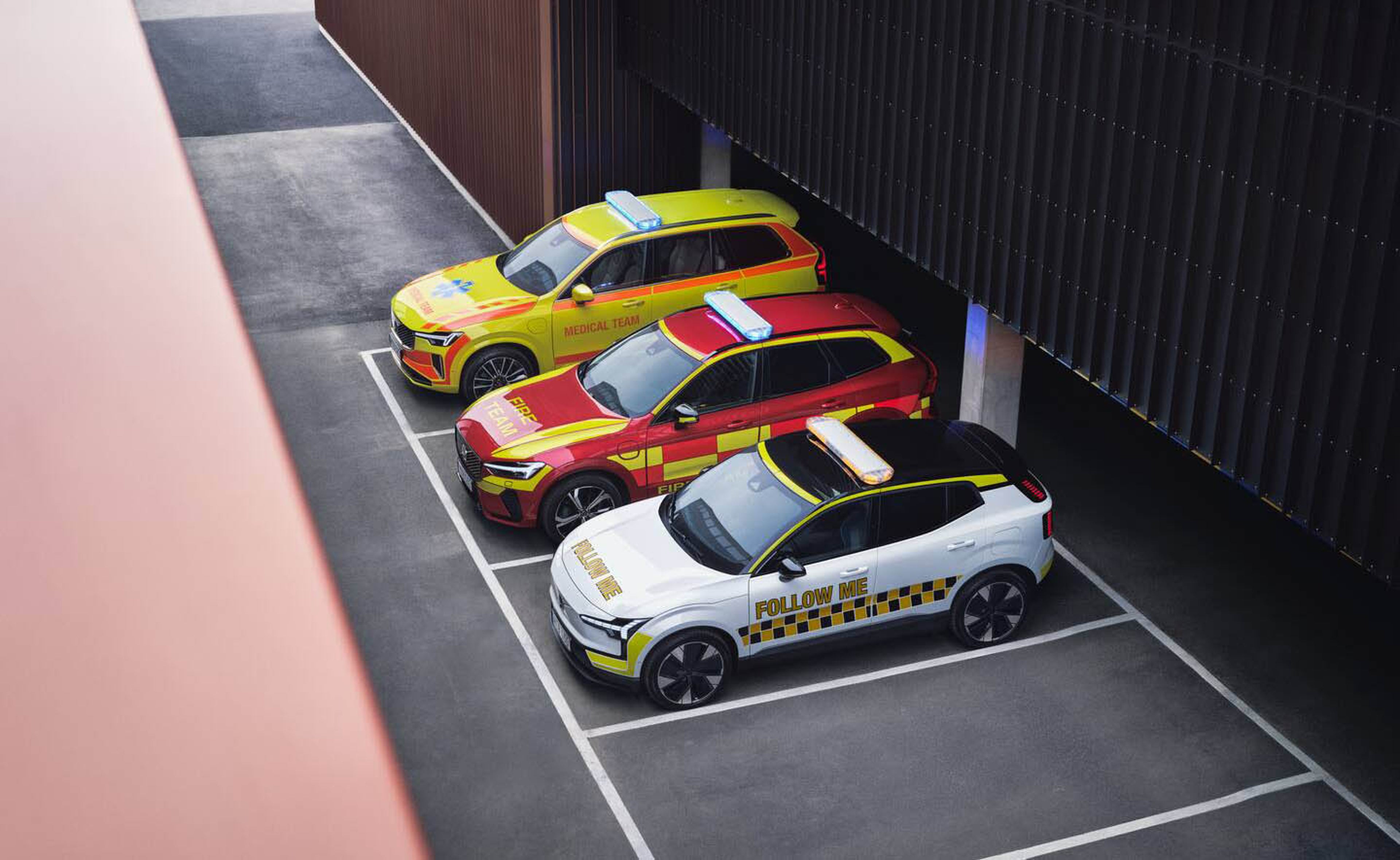 Три возила за итни случаи и сервиси „Volvo“ паркирани едно до друго со светла за итни случаи на врвот.