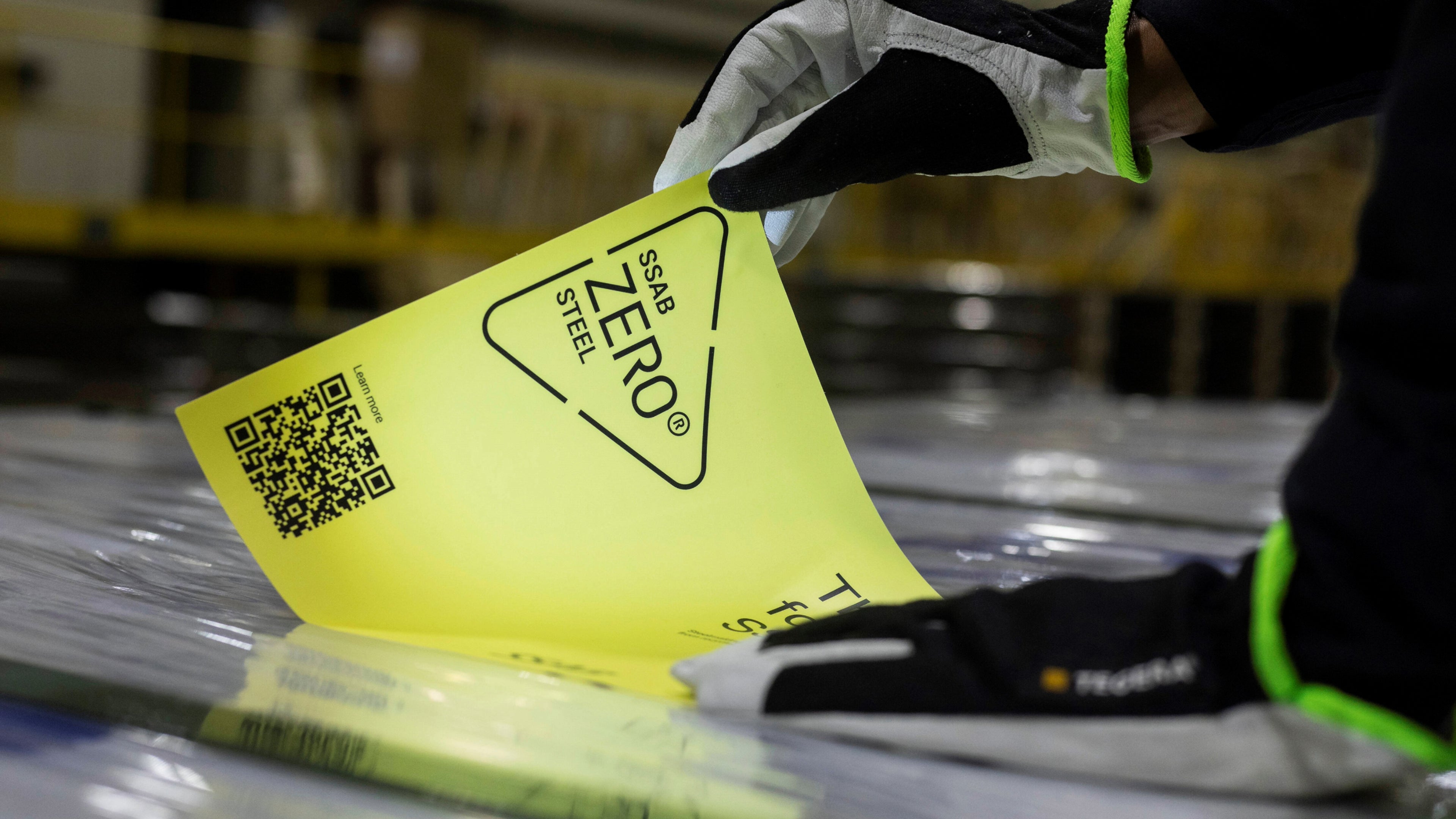 close de duas mão a colarem um autocolante amarelo num capo de um volvo