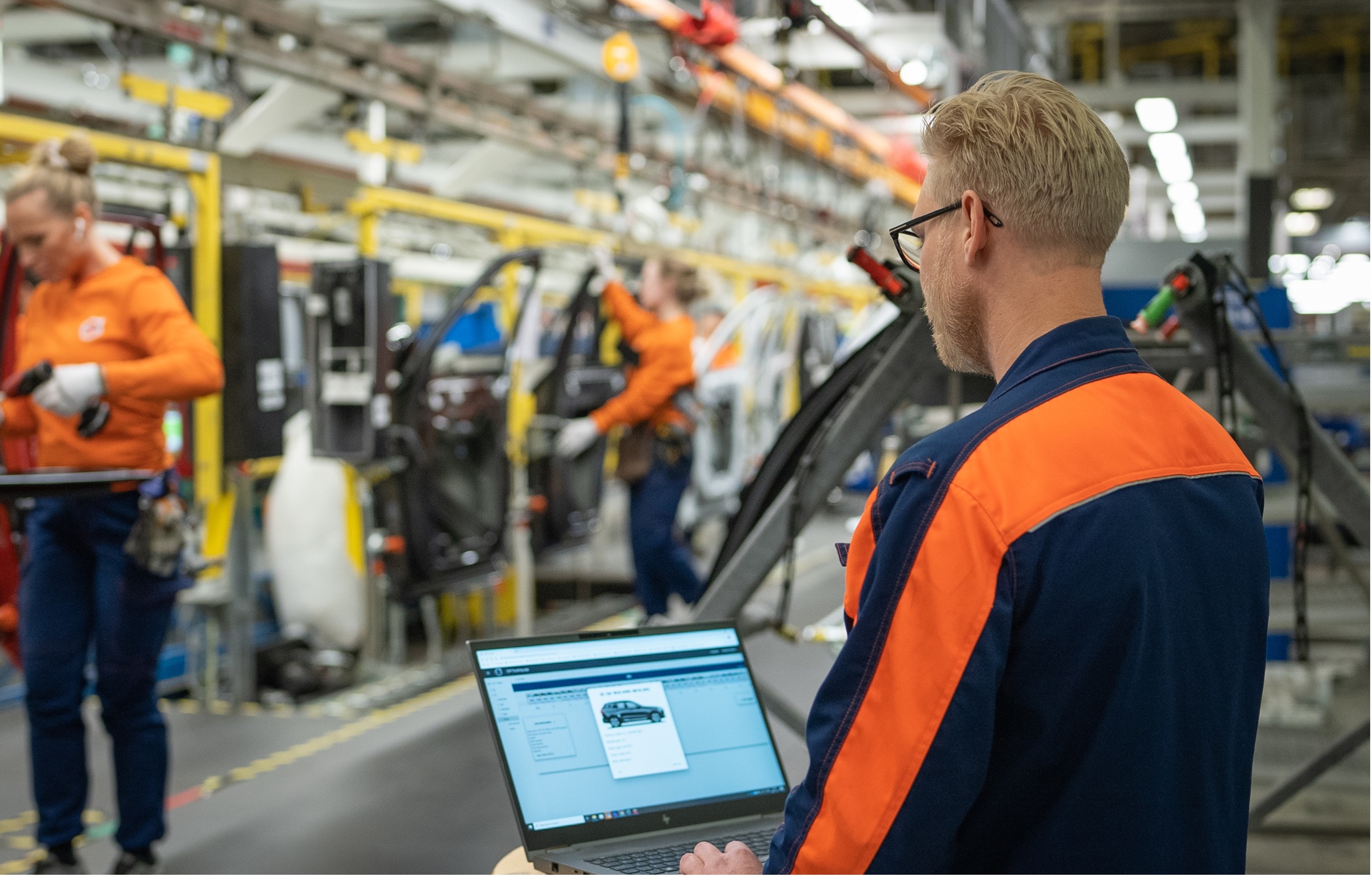 Volvo Cars employee working on a laptop adjacent to the production line at the Volvo Cars Torslanda manufacturing plant.