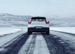 Изглед отзад на бял автомобил Volvo XC40, който се движи по заледен път.