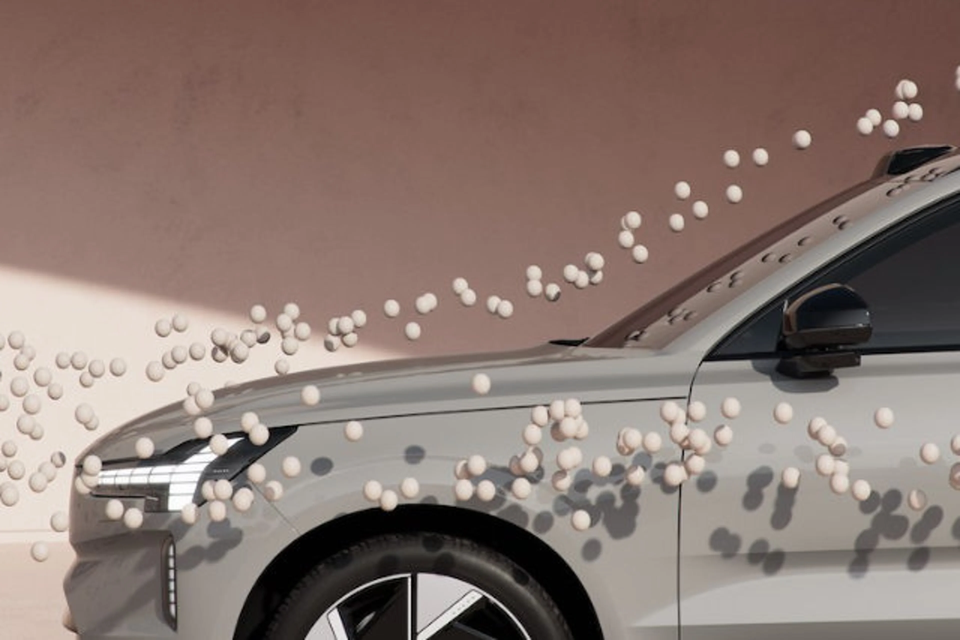 Des objets qui ressemblent à des balles volent autour d'une Volvo EX90 pour illustrer l'aérodynamisme.