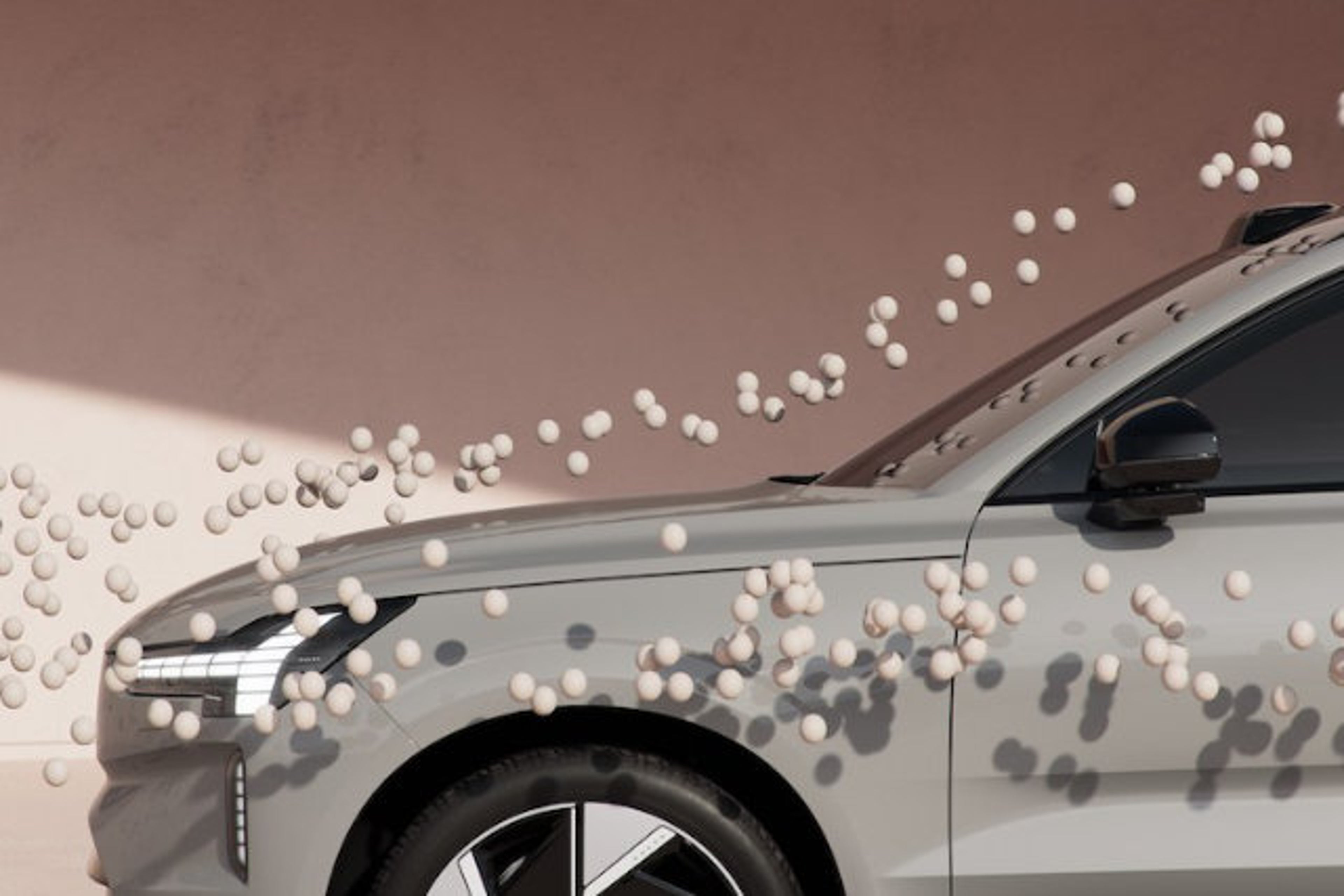 Des objets qui ressemblent à des balles volent autour d'une Volvo EX90 pour illustrer l'aérodynamisme.