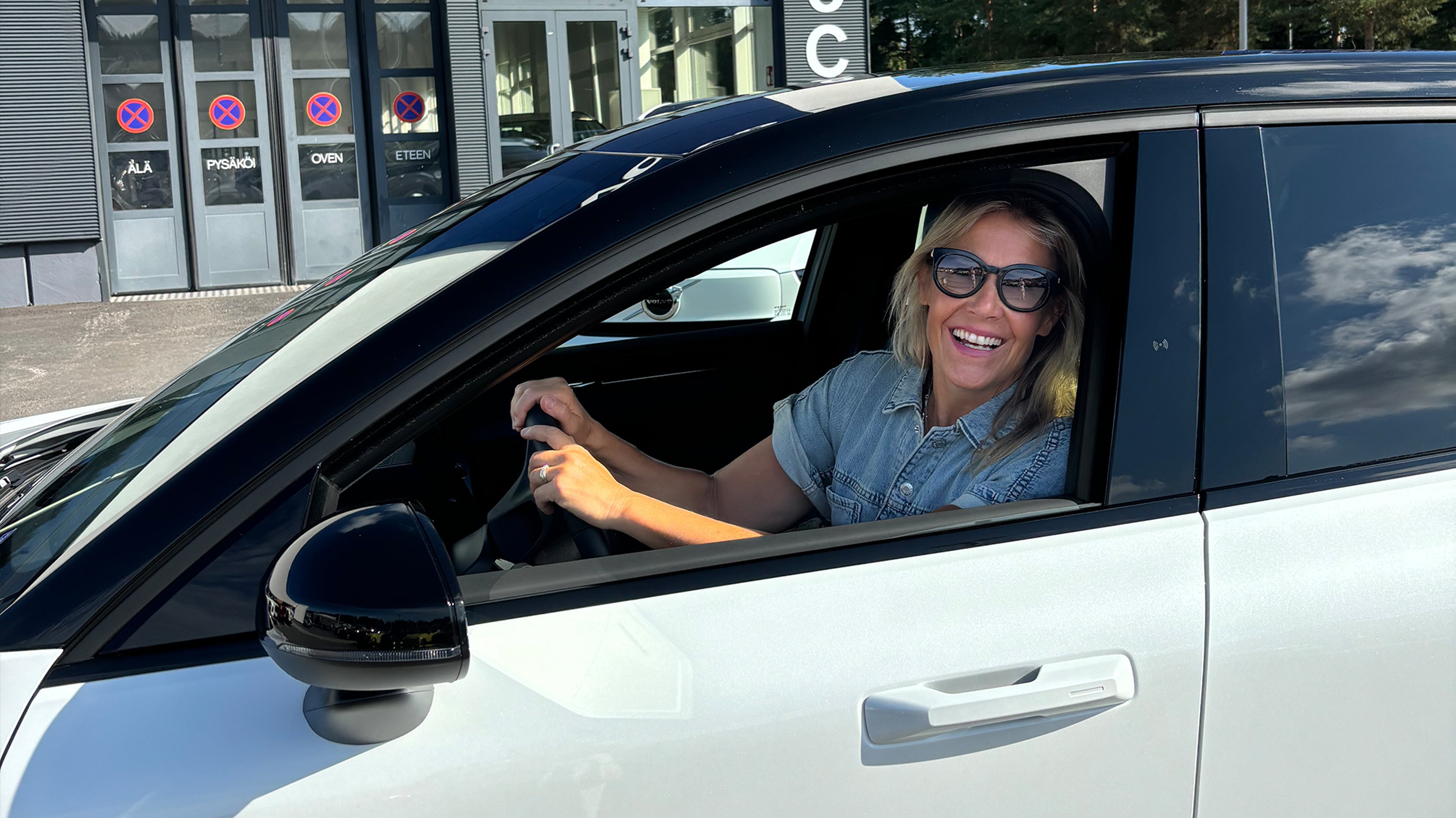 Ella Kanninen ajaa Crystal White -väristä Volvo EX30 täyssähköautoa hymyillen.