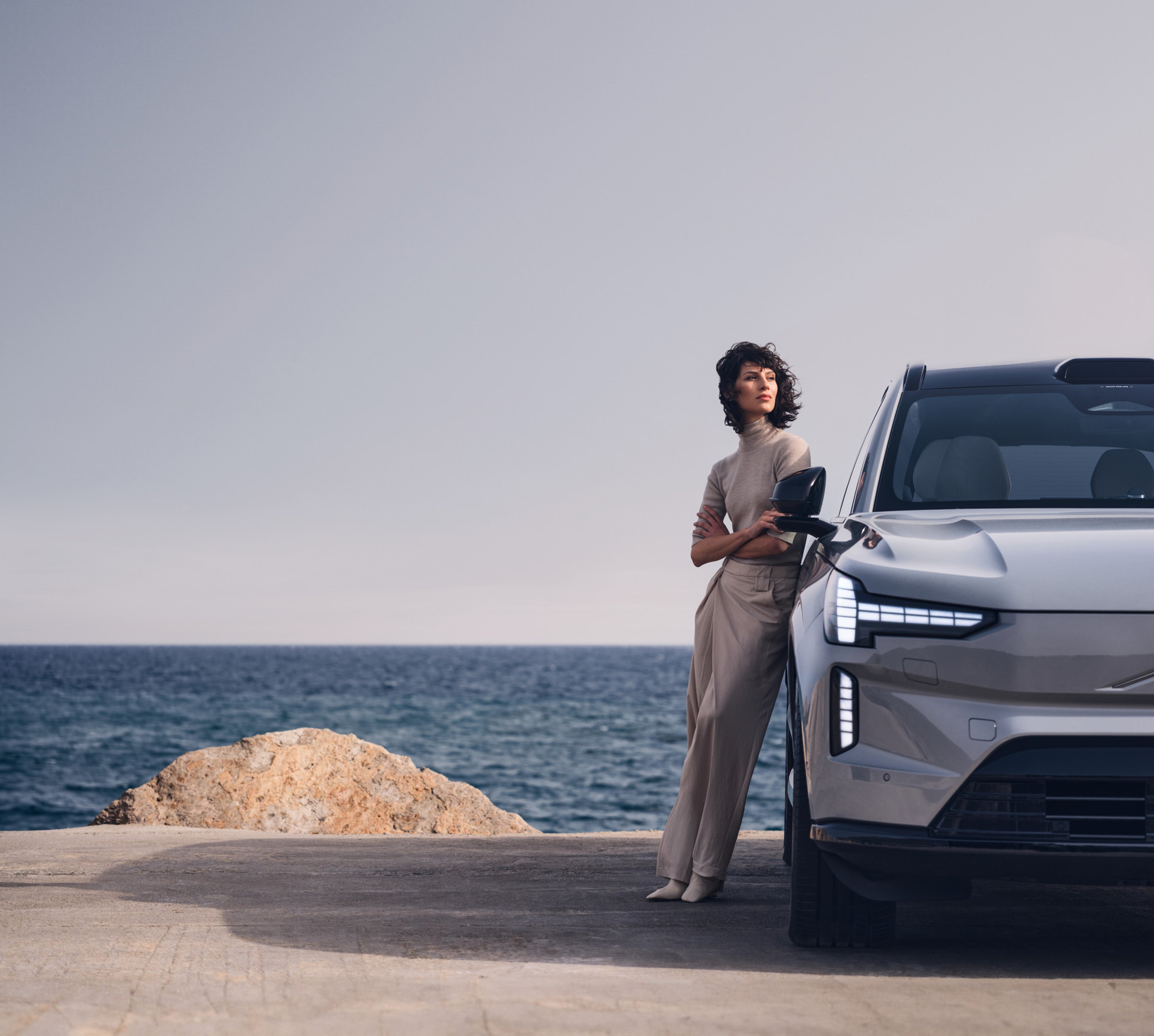 A woman standing in front of a Volvo EX90