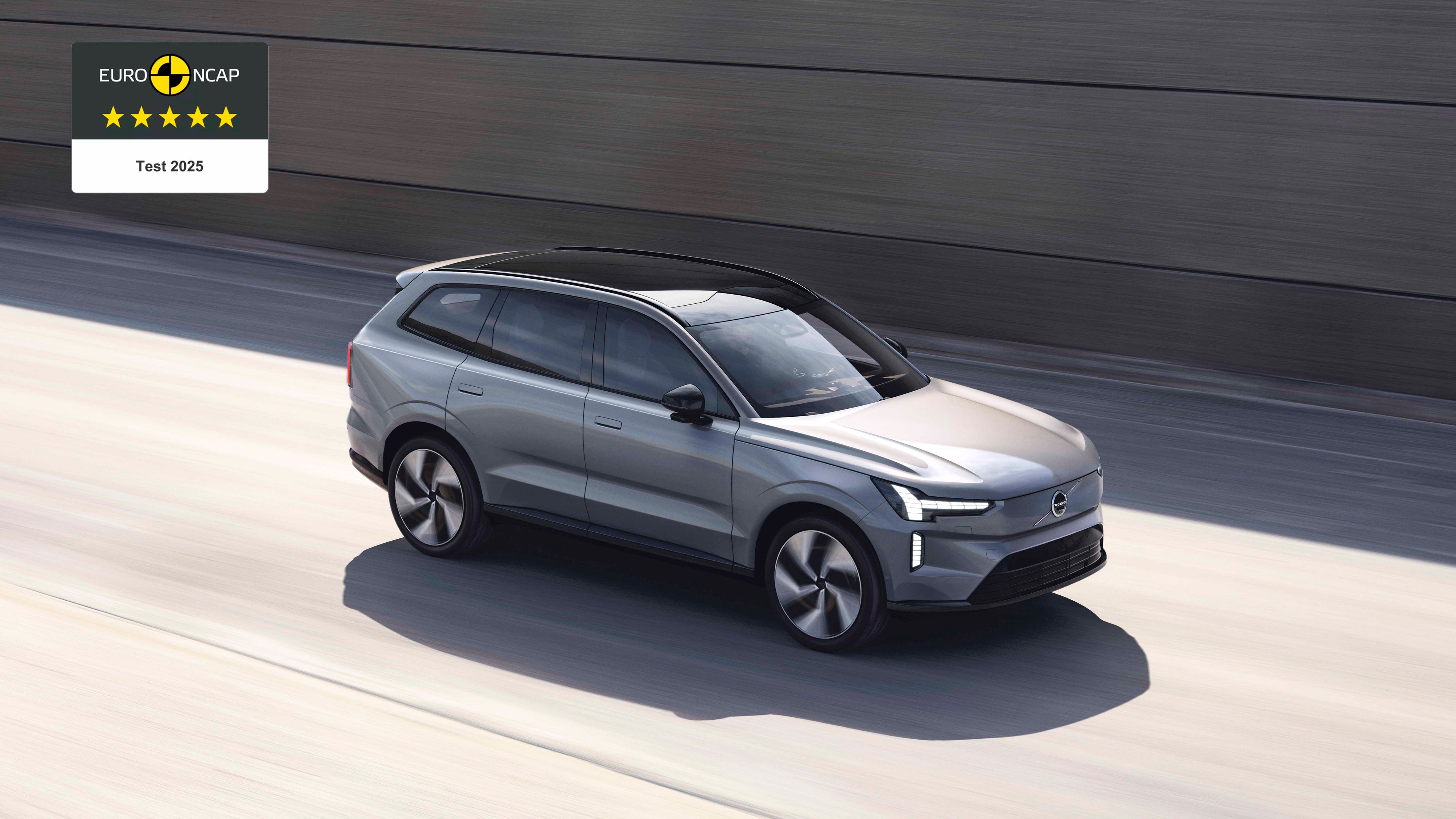 Volvo EX90 SUV vista lateral superior en un color gris atravesando una calle y destacando sus faros LED