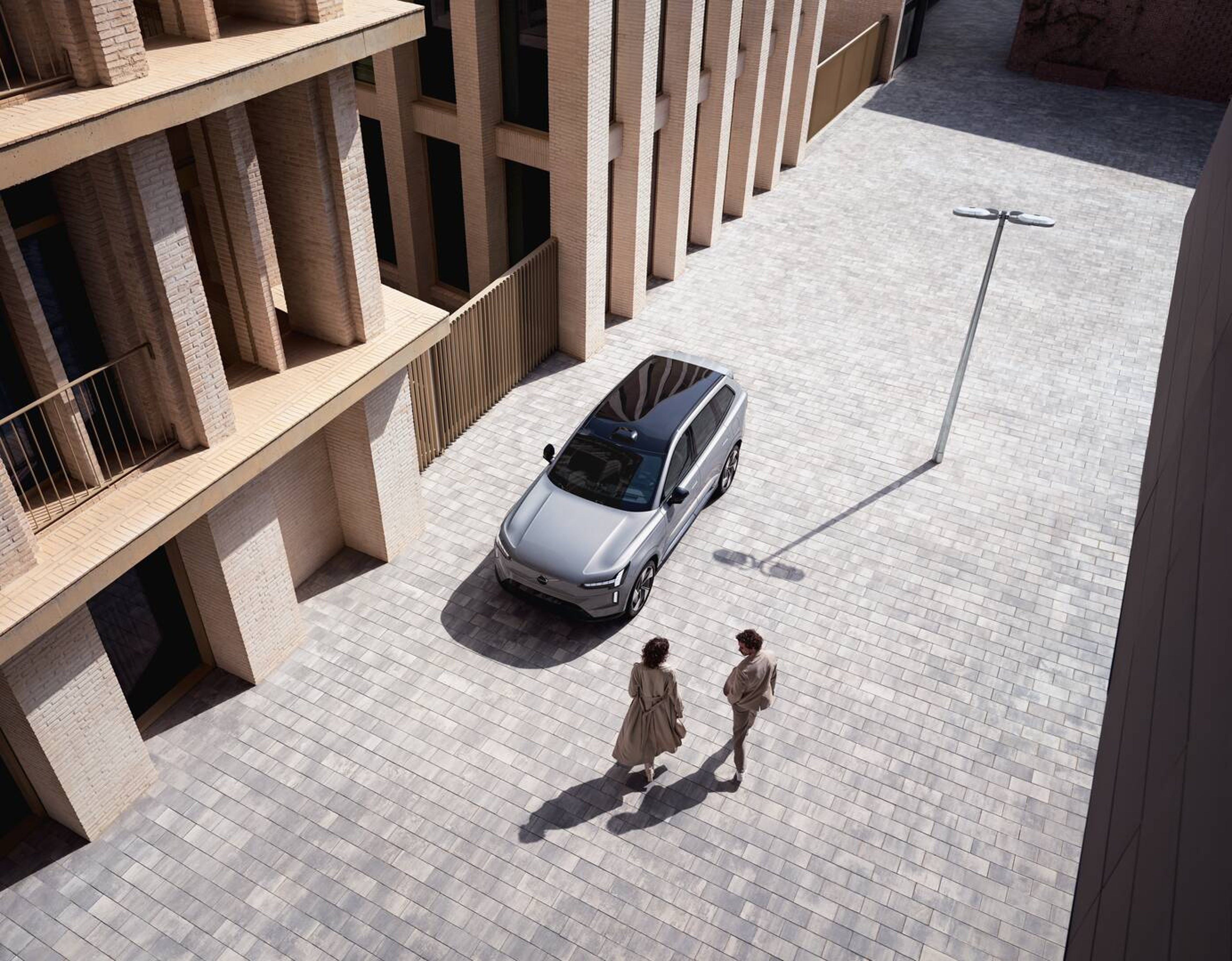 Volvo EX90 dans un milieu urbain avec deux personnes s’en approchant