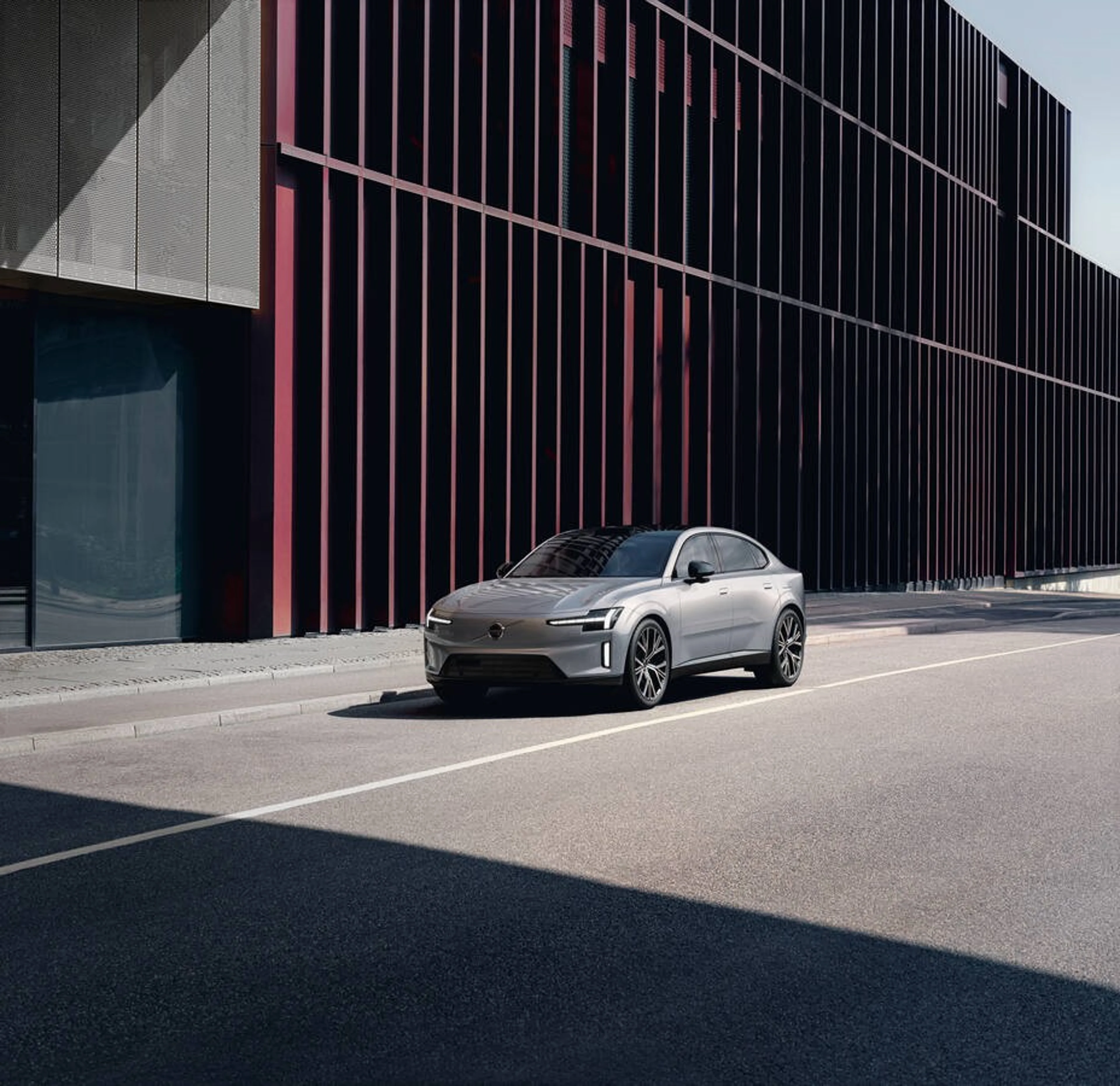 Silver sedan with black wheels parked beside modern building.
