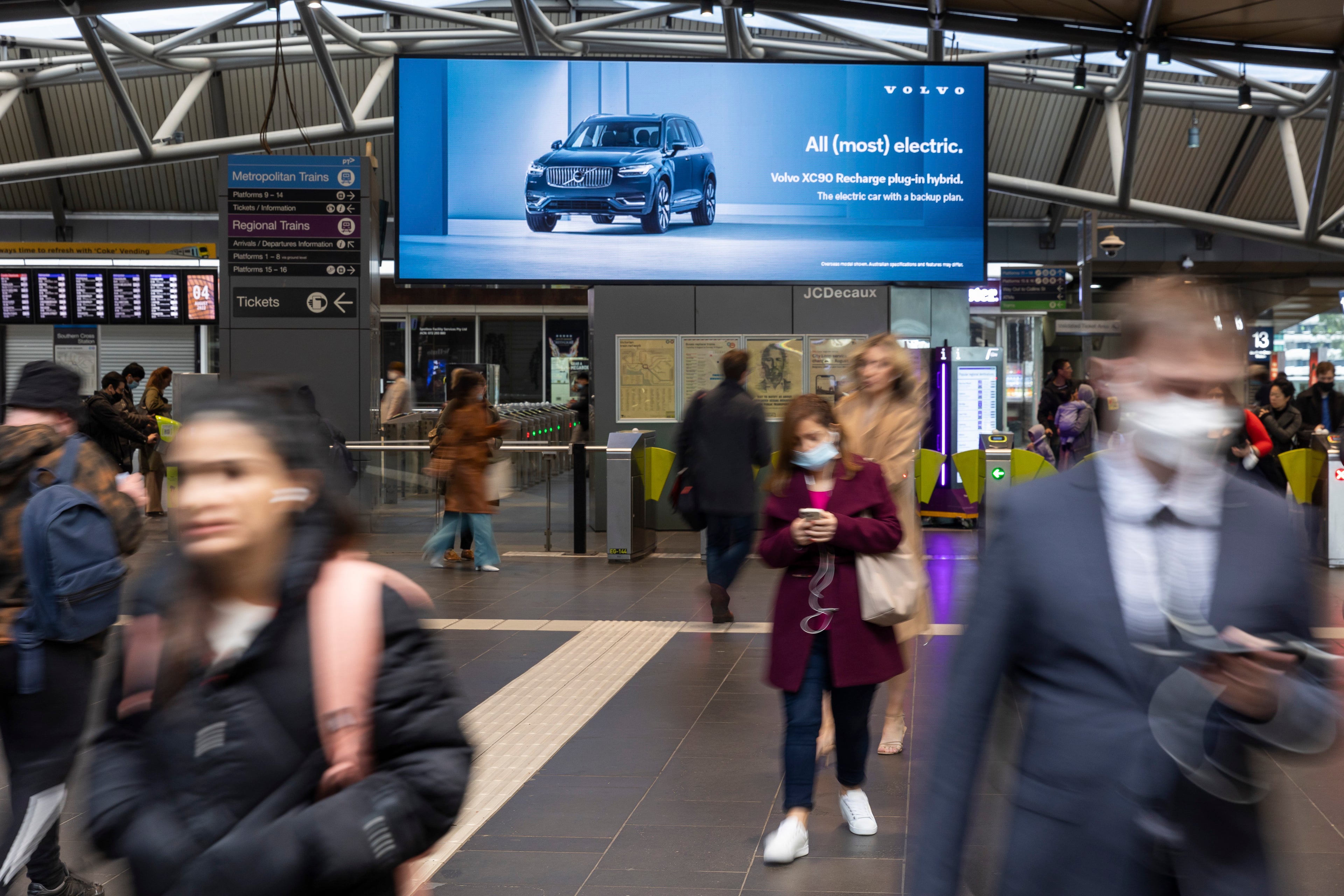 People walking under billboard displaying XC90 recharge