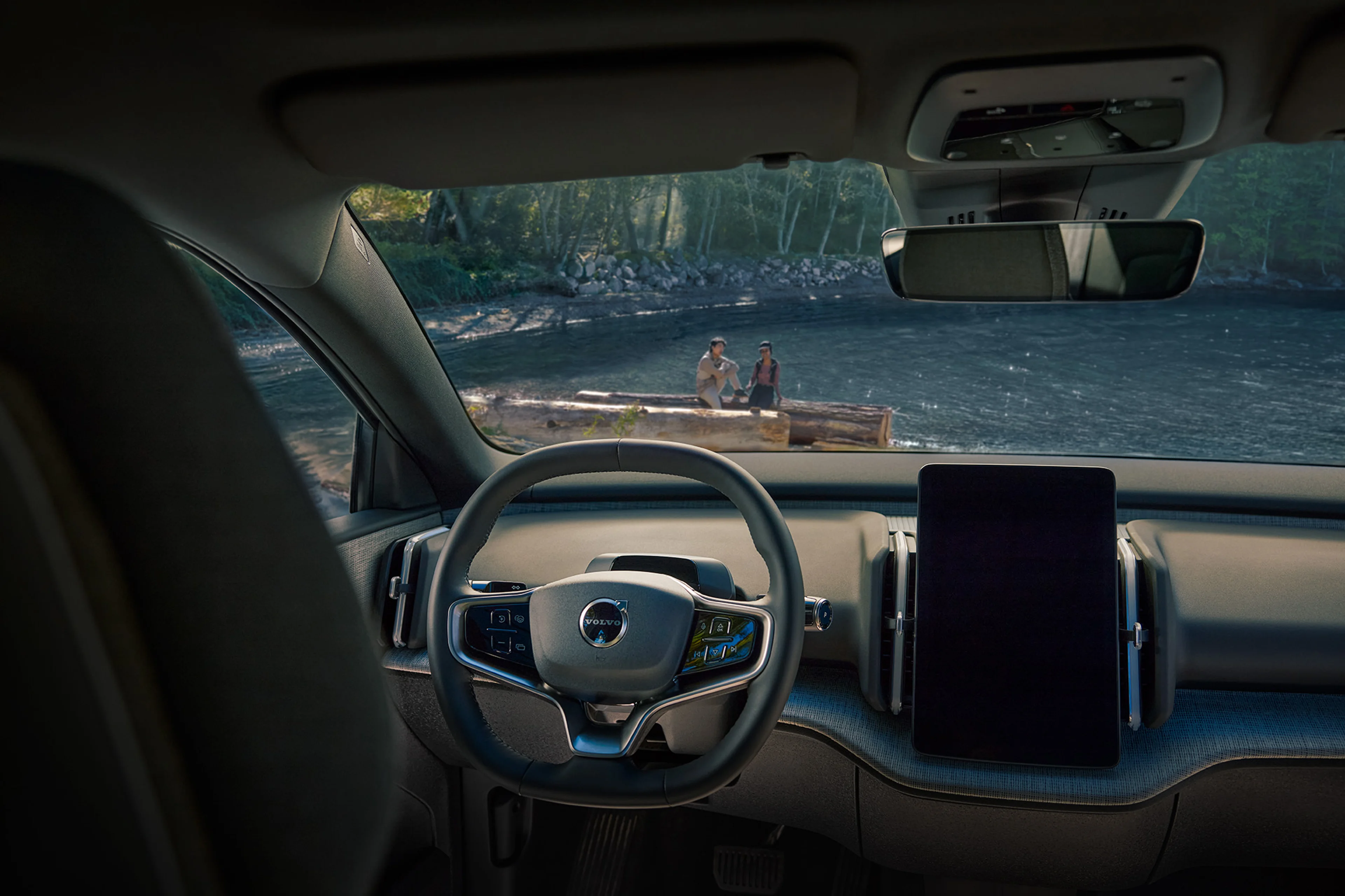 El amplio y moderno interior del Volvo EX30 Cross Country, estacionado junto a una serena orilla del lago.