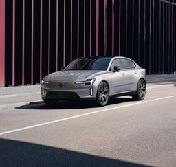 Silver sedan with black wheels parked beside modern building.