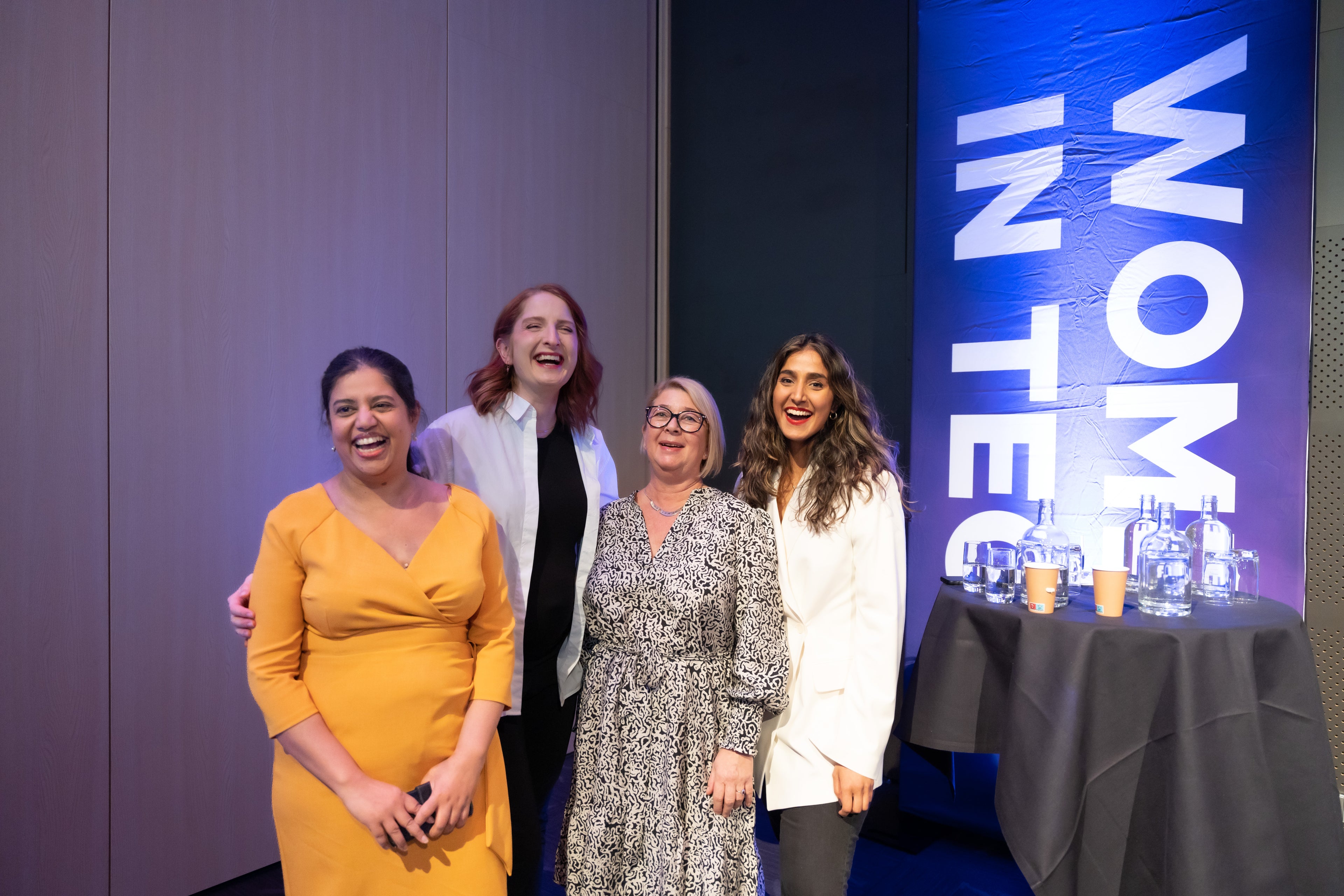 Vier Frauen lachen zusammen bei der Podiumsdiskussion der Women in Tech