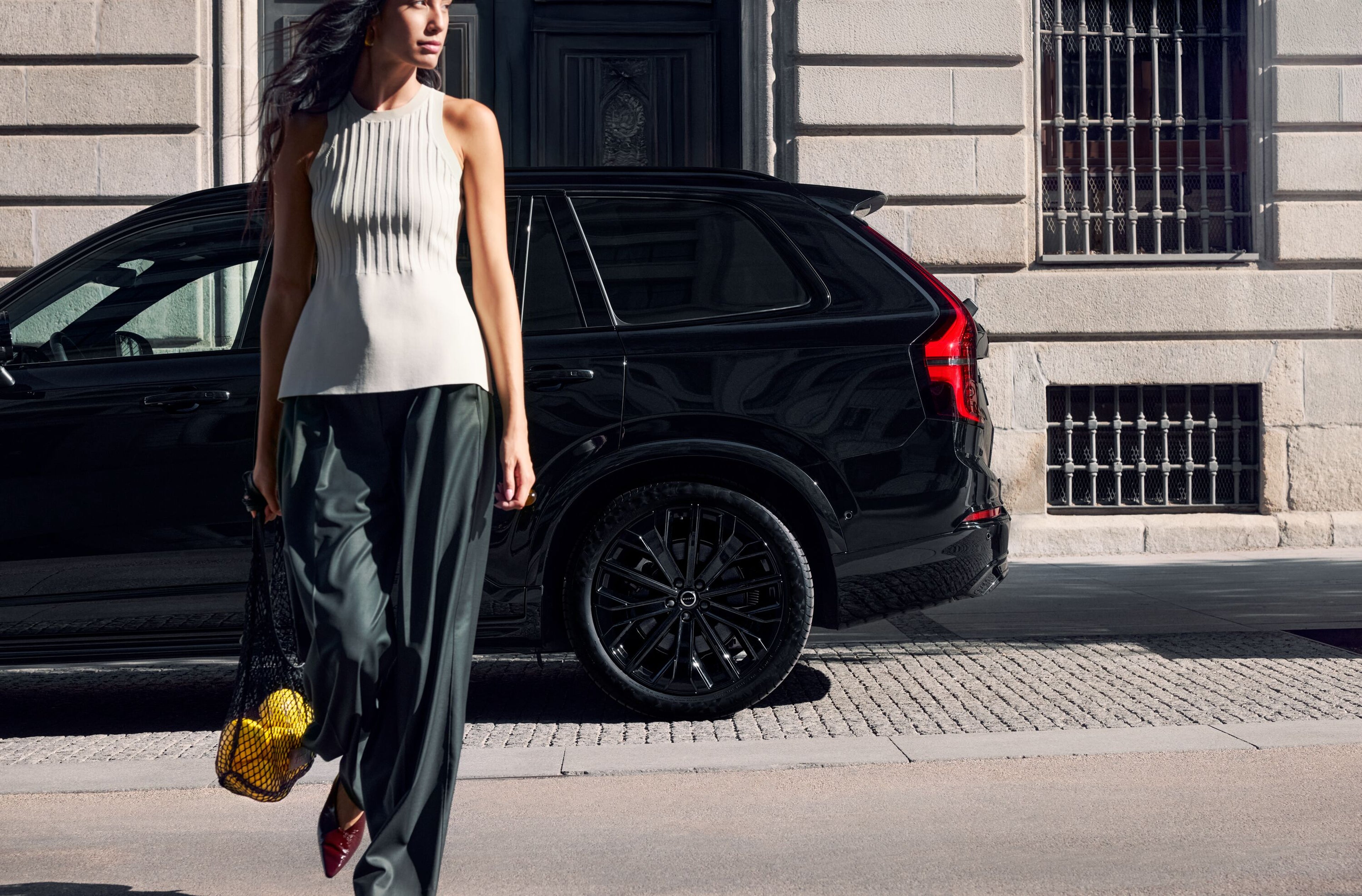 žena kráčajúca pri Volvo XC90 black edition
