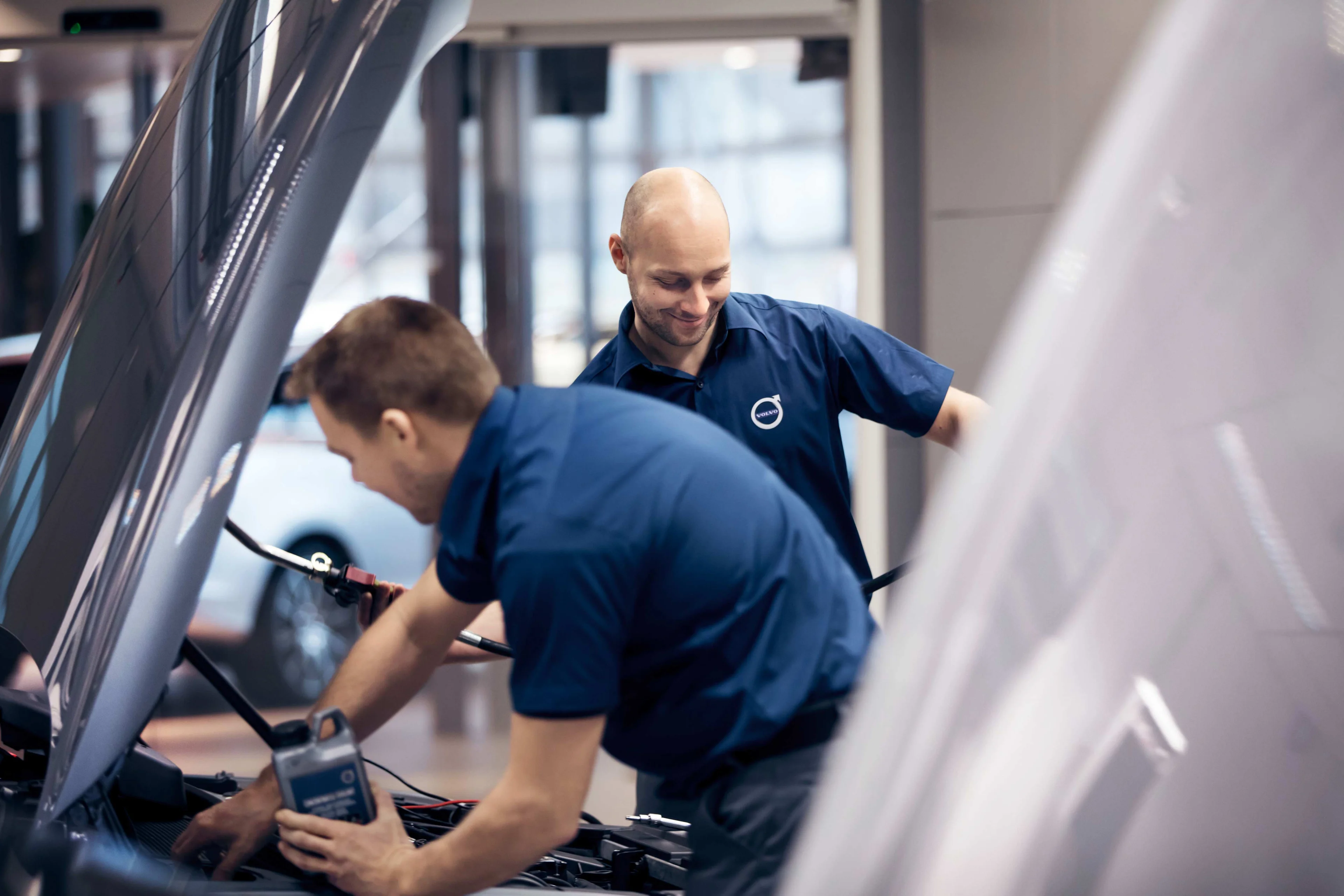 Kaksi Volvo omamekaanikkoa vaihtaa huoltaa autoa.