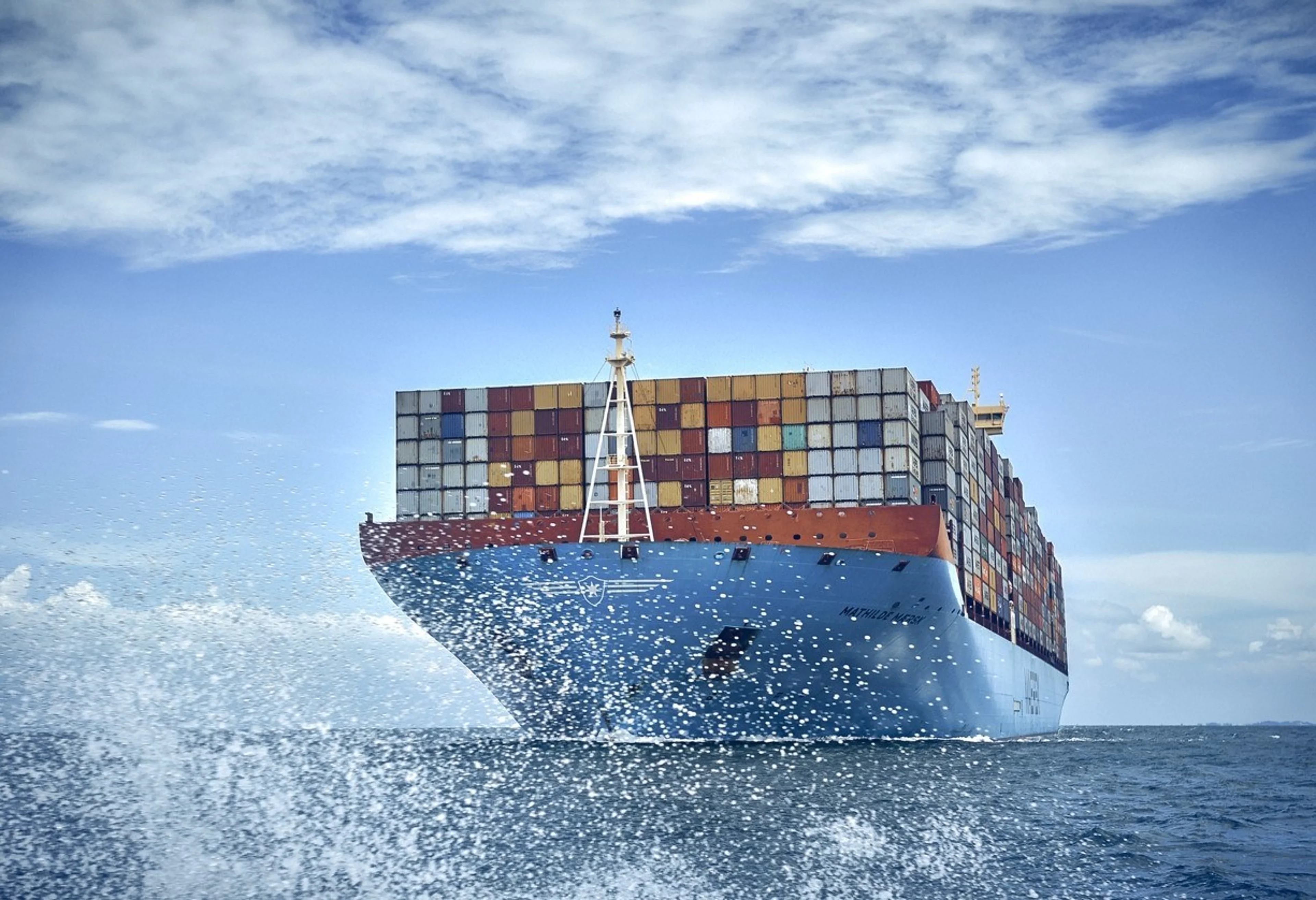 Grosses Übersee-Container-Schiff fährt über den Ozean und ist voll beladen mit vielen Containern.