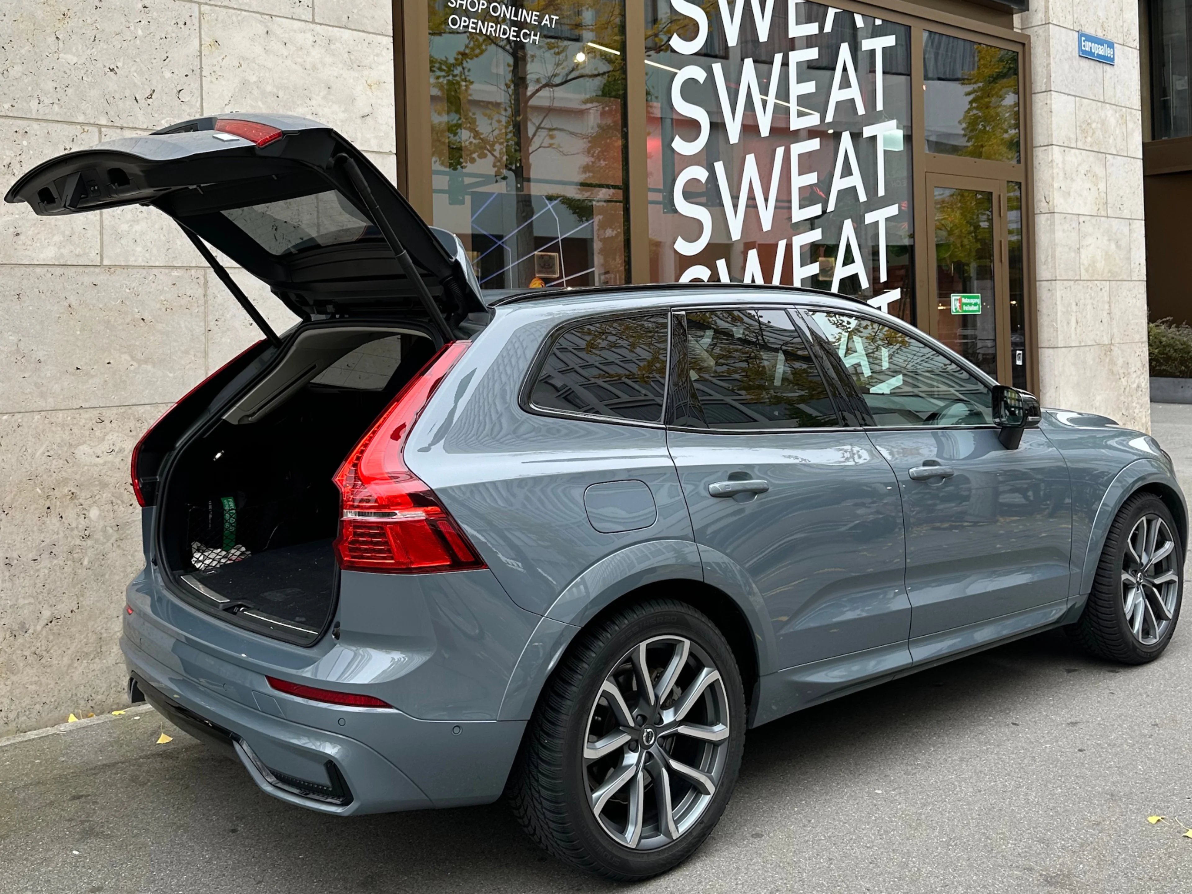 Ein grau-blauer Volvo XC60 von hinten mit geöffneten Kofferraum.
