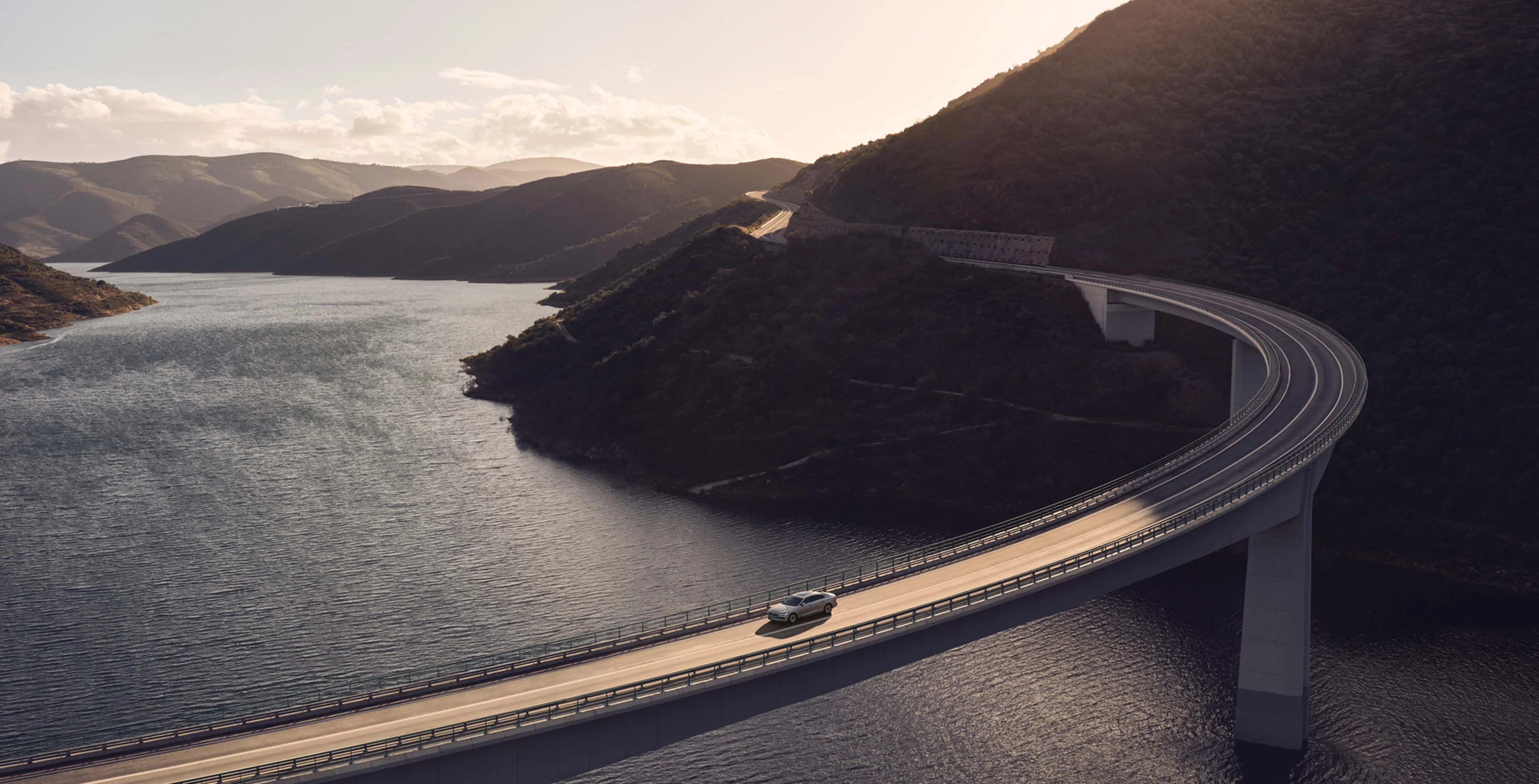Volvo S90 ajaa vesialueen ylittävällä sillalla.