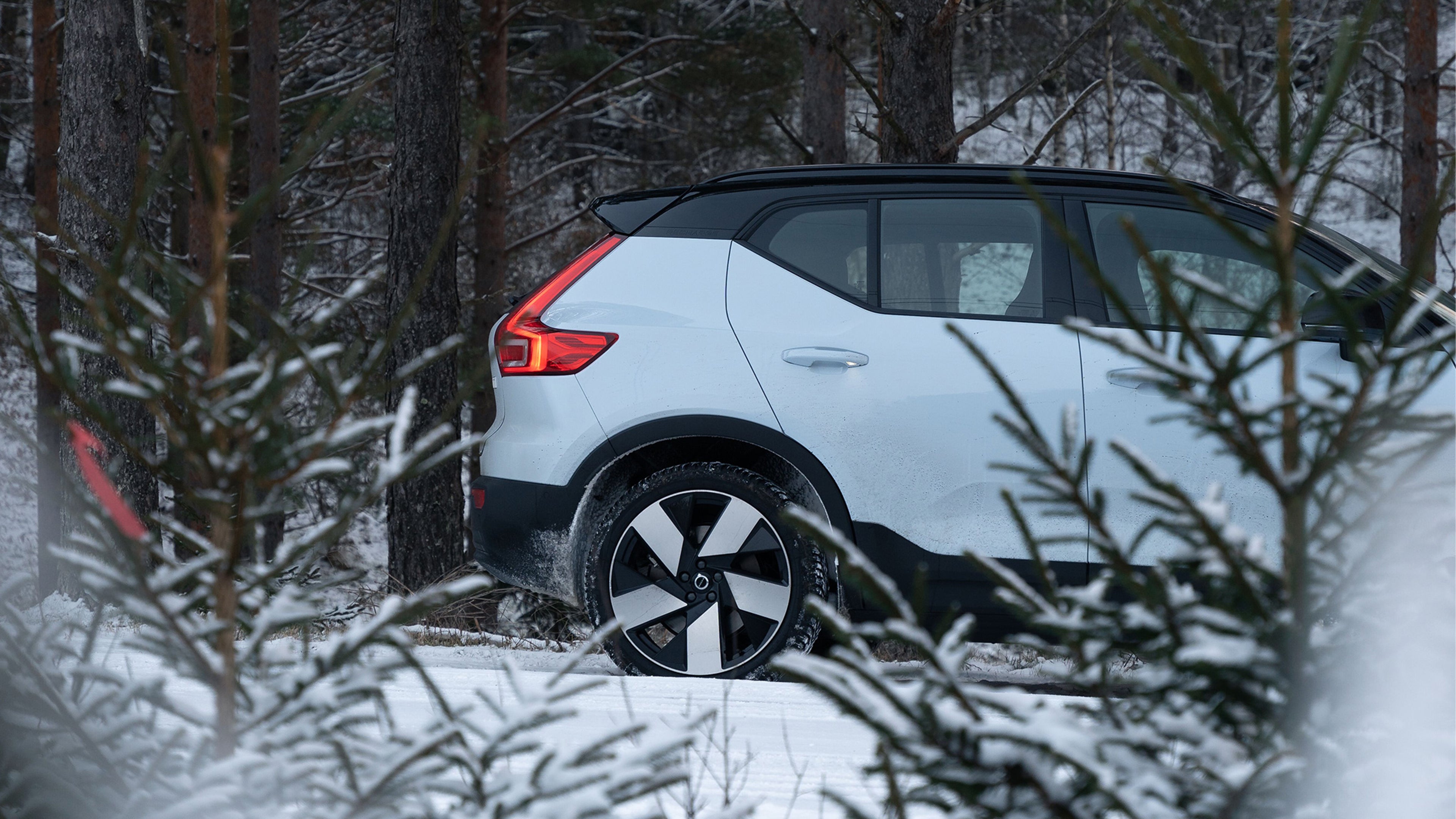 Cloud Blue -värinen Volvo XC40 Recharge täyssähköauto lumisessa metsässä.
