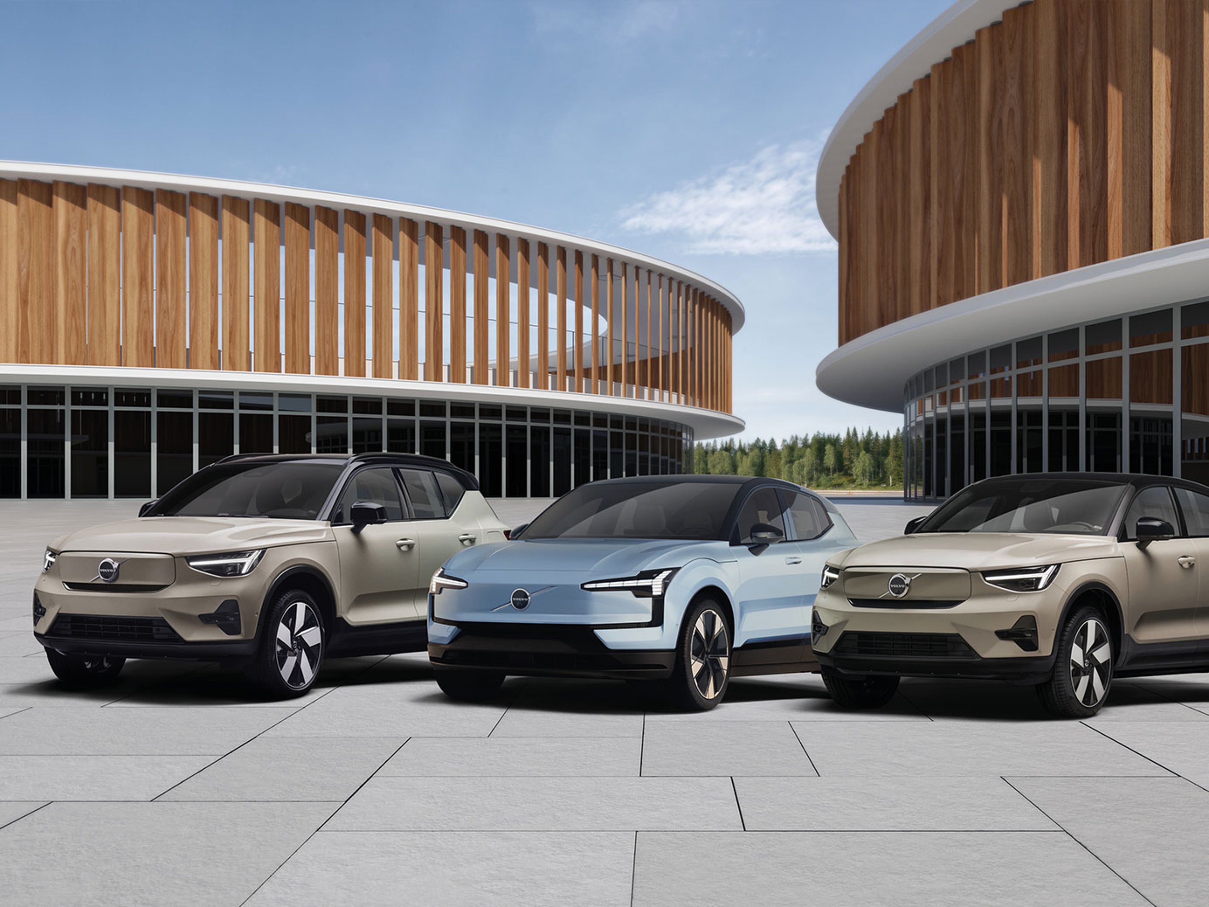 Gamme Volvo électrique : trois modèles inspirants devant une architecture en bois moderne, alliance parfaite entre nature, design et avenir durable.