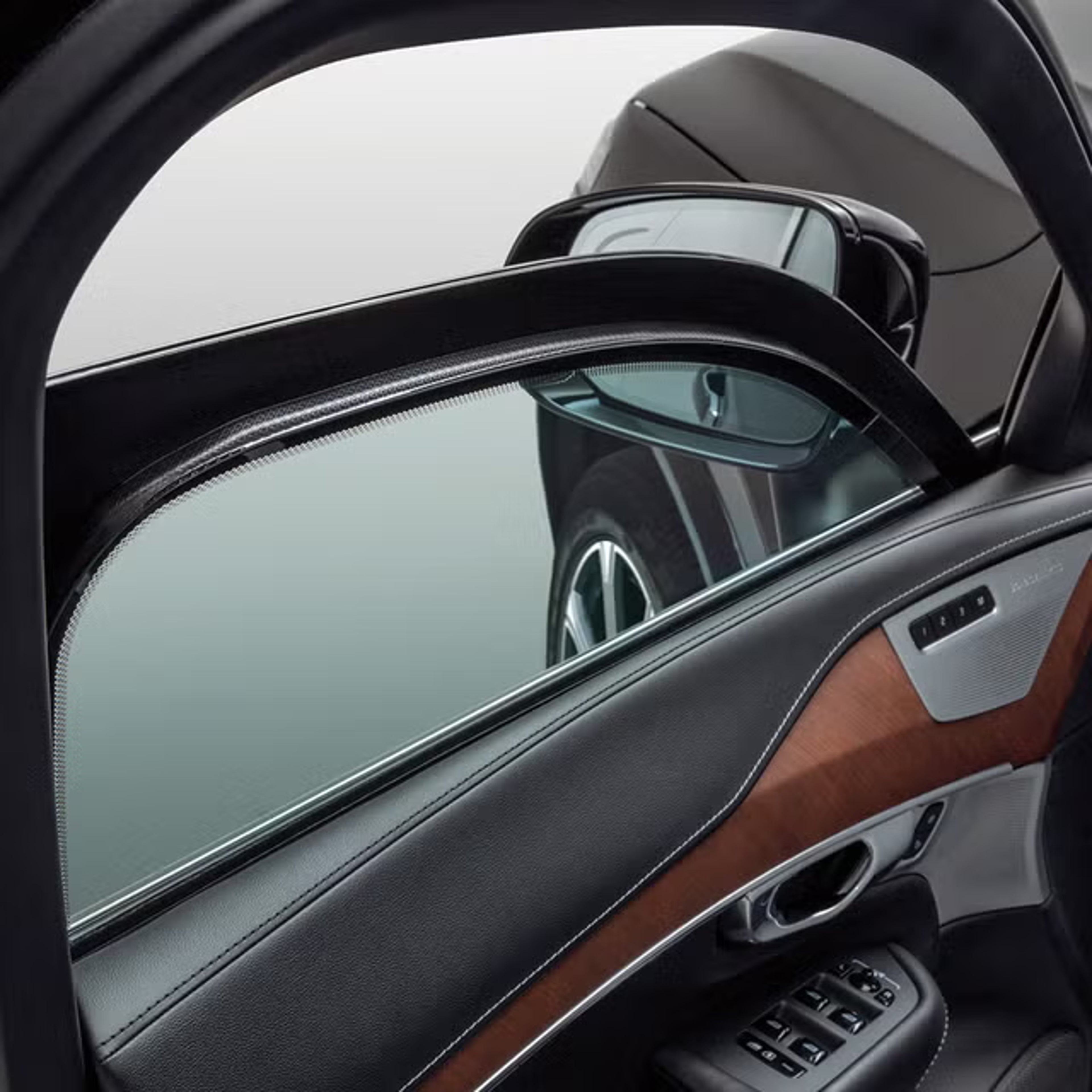 Detailní pohled na částečně stažené okno levých předních dveří znázorňující tloušťku vrstveného skla v lehce pancéřovaném voze Volvo.