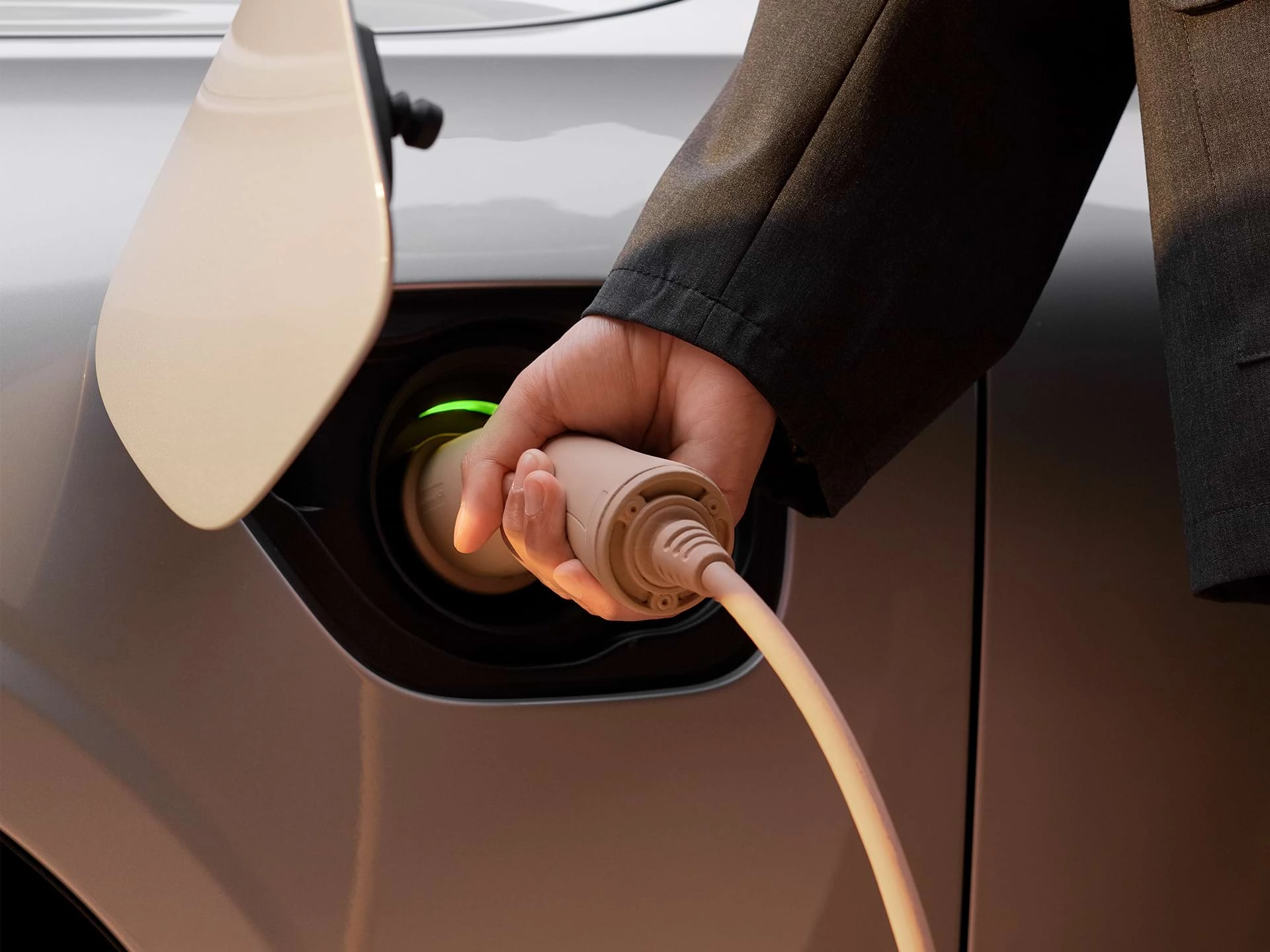 Снимок крупным планом руки мужчины, подключающей зарядное устройство к зарядному порту автомобиля Volvo.