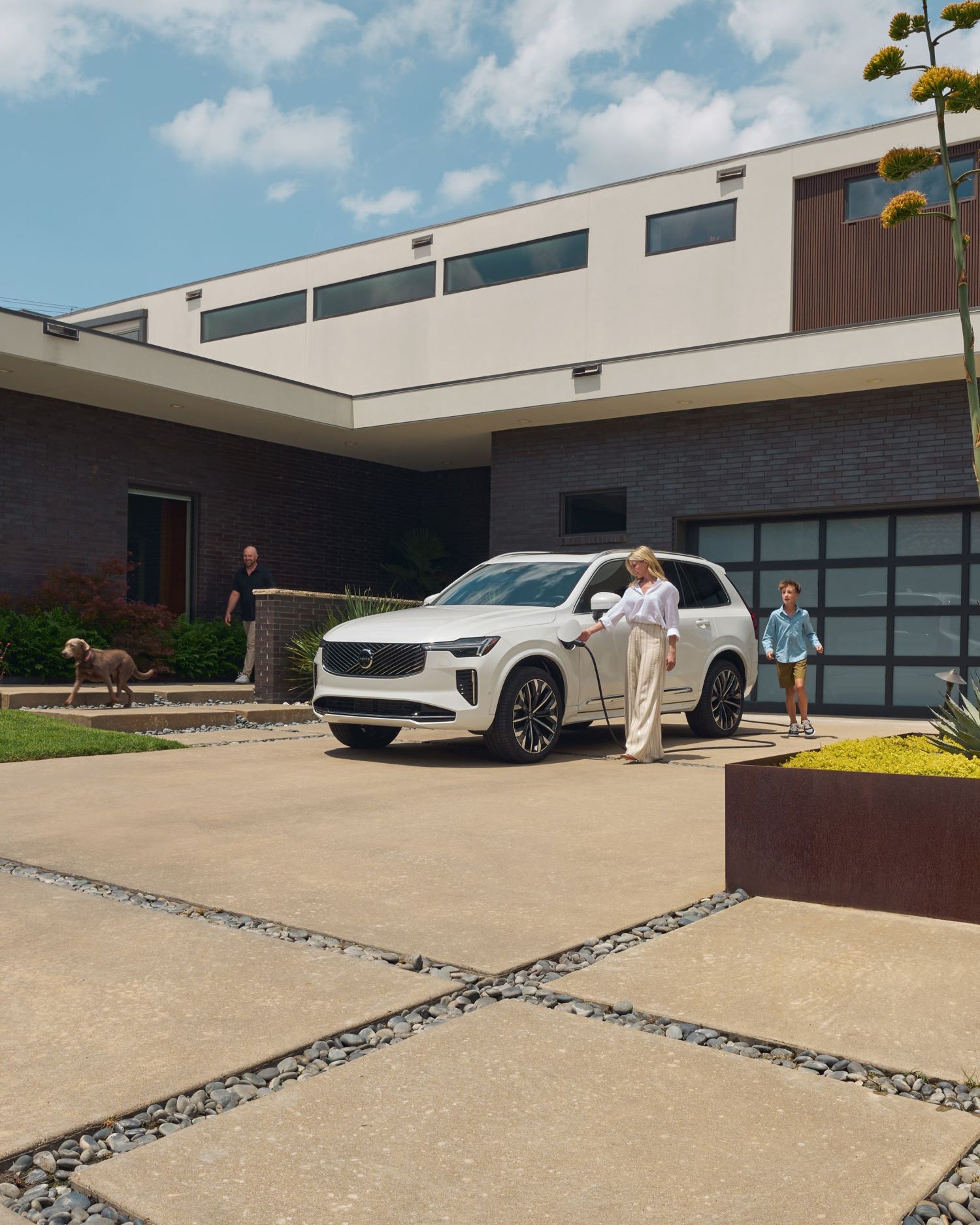 Woman charging Volvo XC90 at home with family