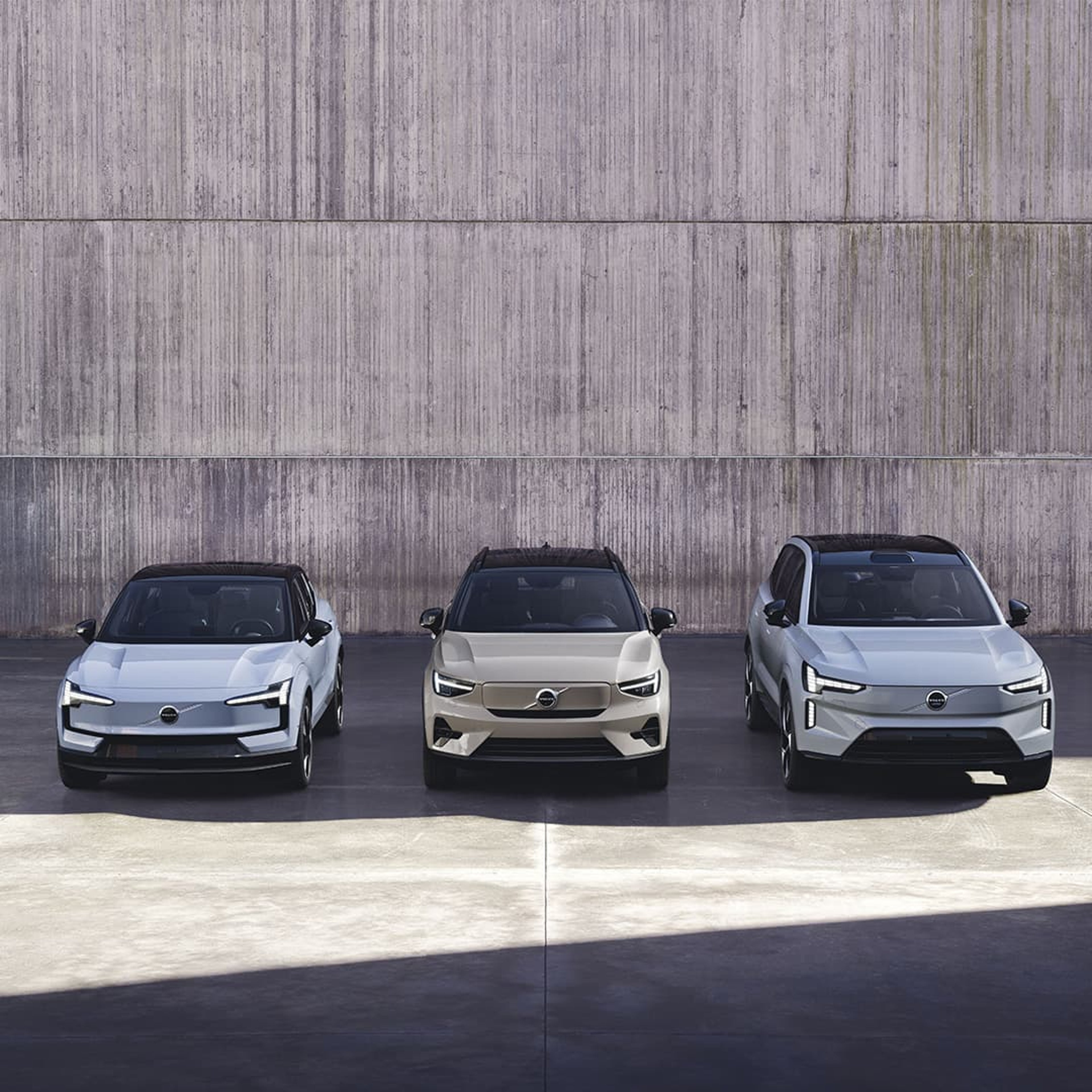 Vy framifrån av Volvo EX30, EX40 och EX90 parkerade sida vid sida på en parkeringsplats.