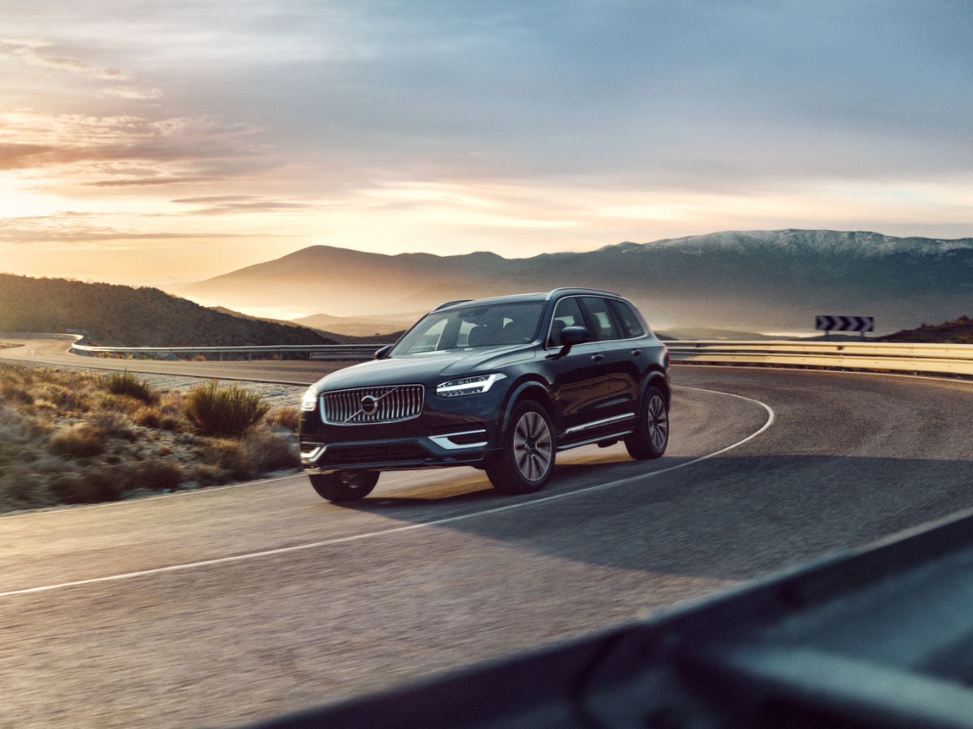 Image montrant un homme et un chien marchant à côté d’un Volvo EX90 garé sur une plage.