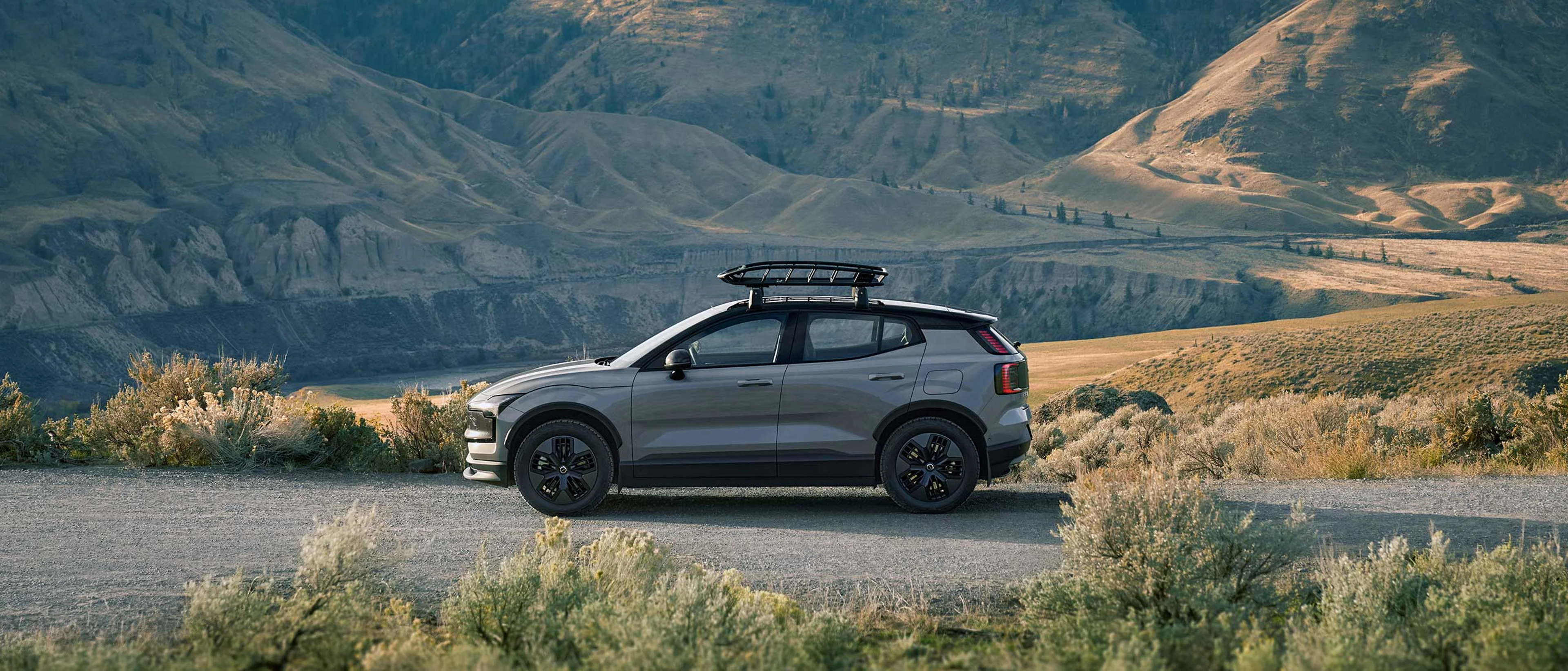 Uma família na praia perto de um Volvo XC90 híbrido plug-in, mudando de roupas de esqui para roupas de banho.