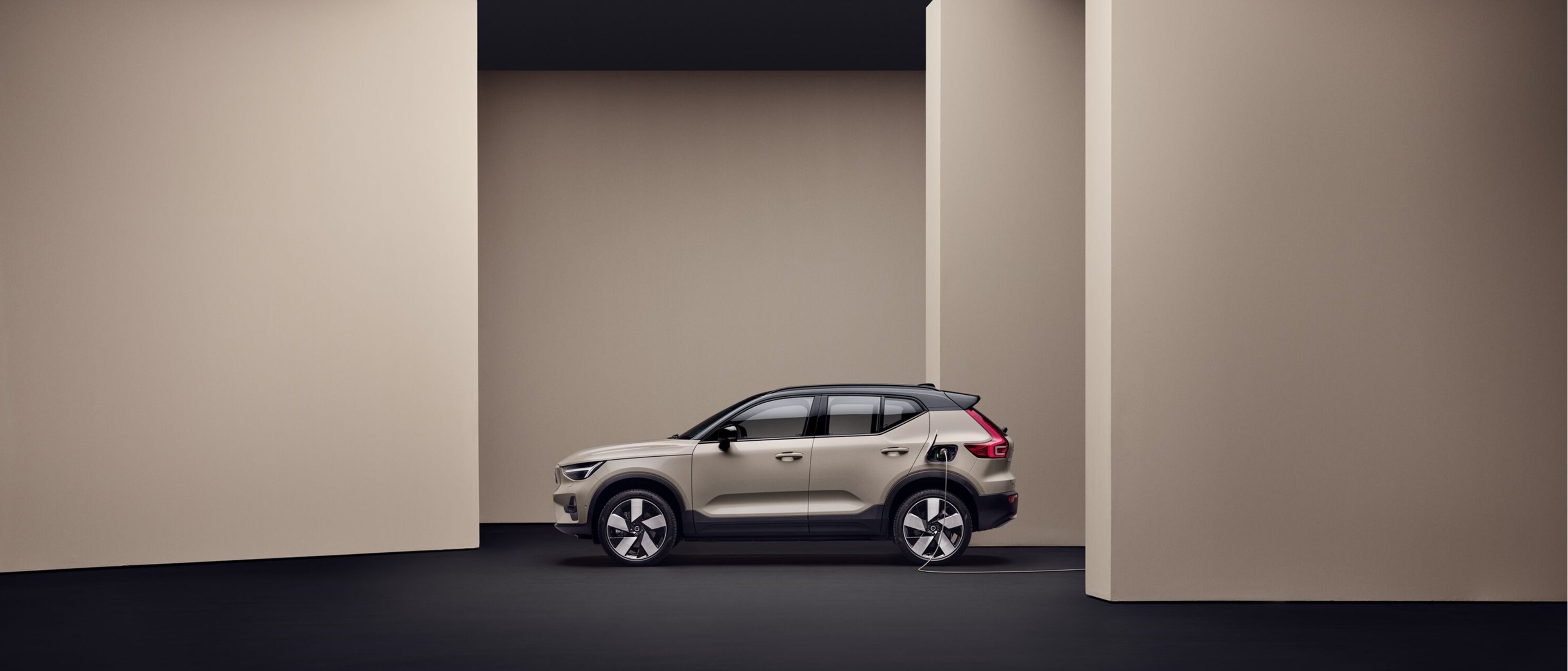 Digital artwork of a Volvo ES90 from below on a floating platform, with a deep red background.