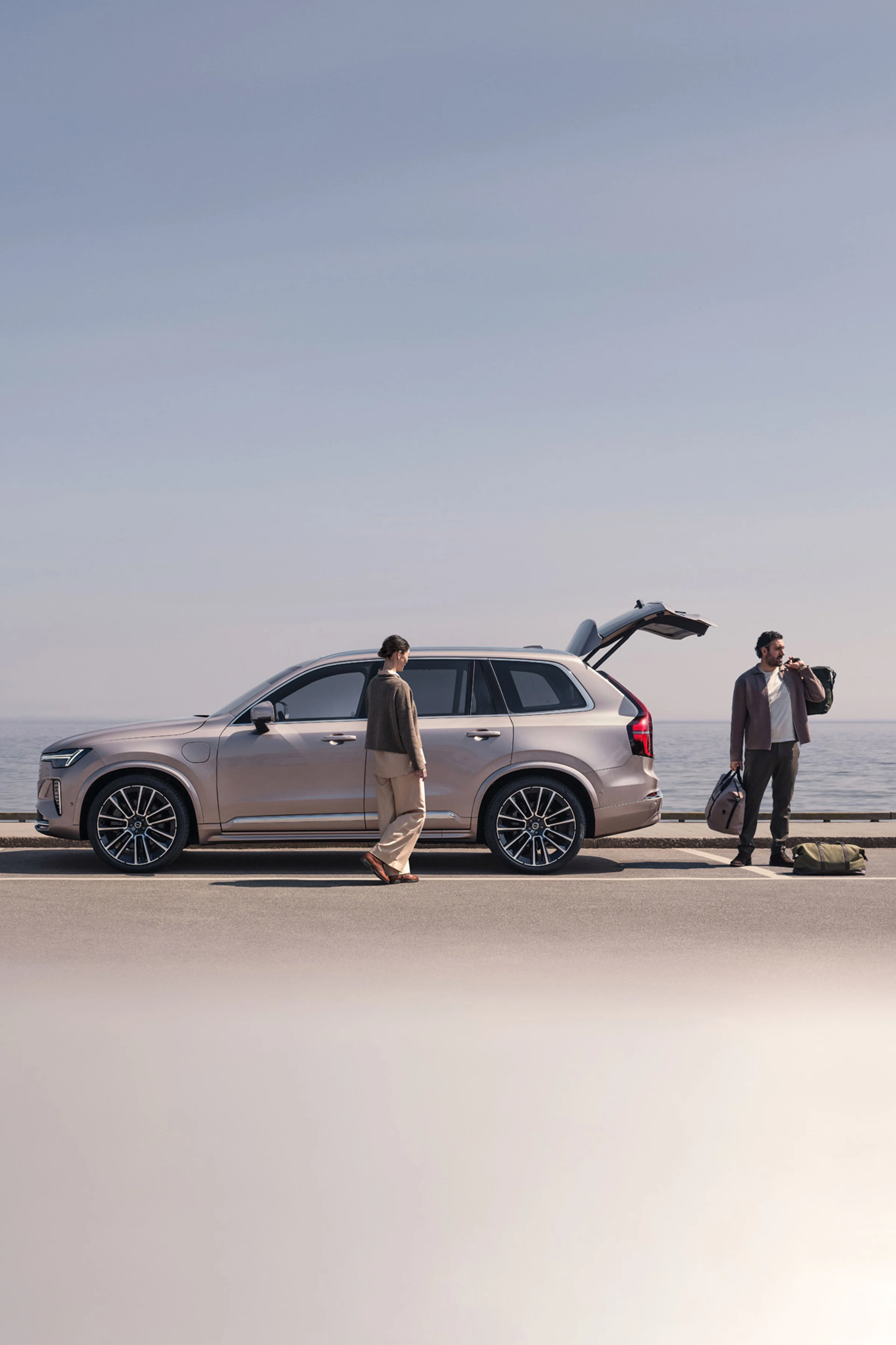 Porodica na plaži, pored plug-in hibrida Volvo XC90, presvlači se iz skijaške odjeće u odjeću za plivanje.