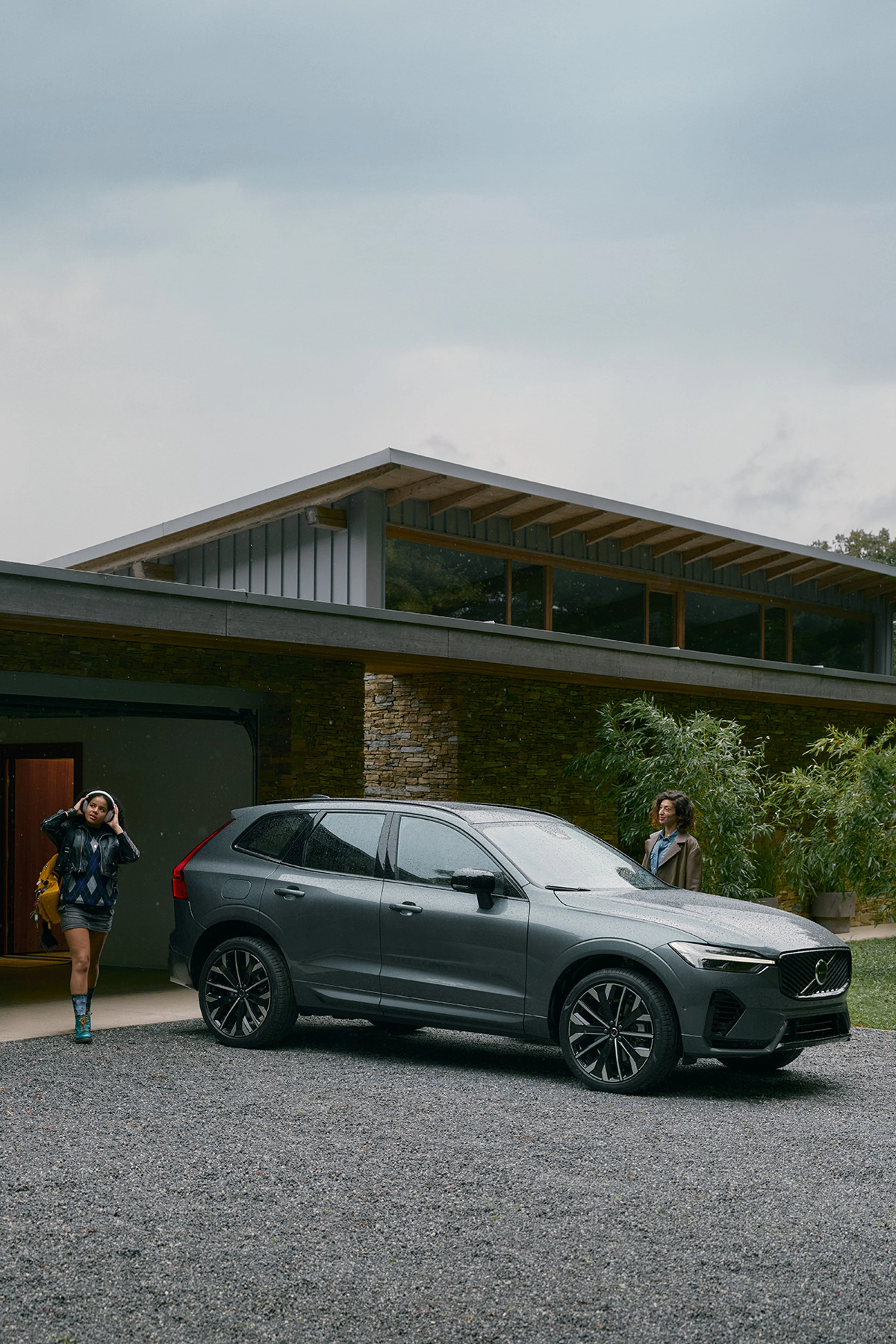 Ein Volvo XC60 Plug-in Hybrid und zwei Personen vor einem Einfamilienhaus.
