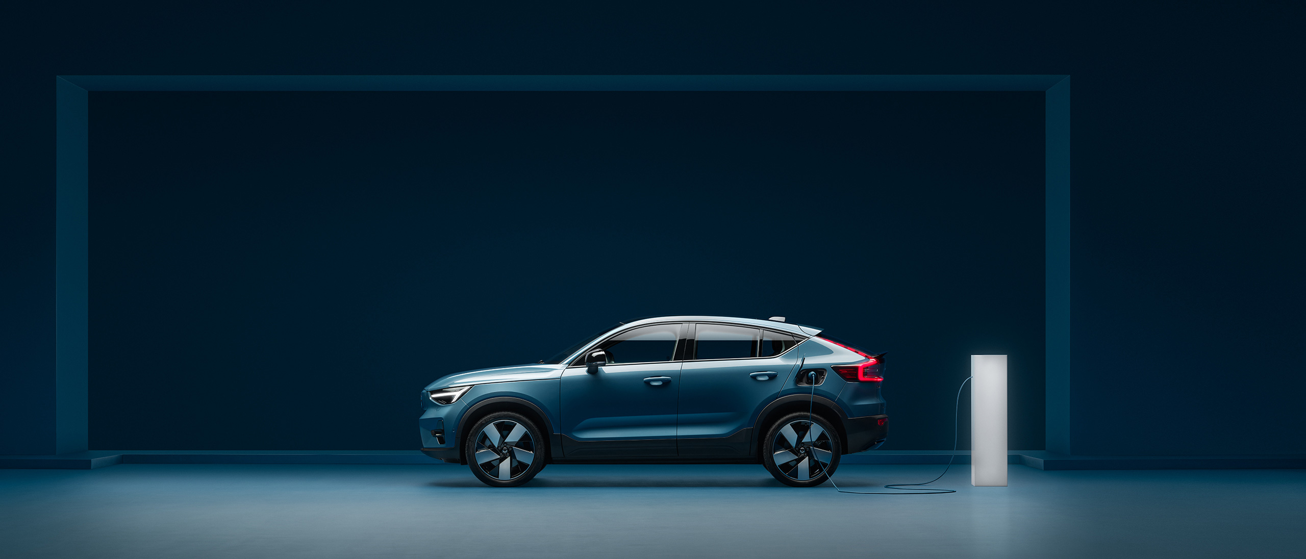 A grey Volvo XC40 full electric SUV being charged in a pink city