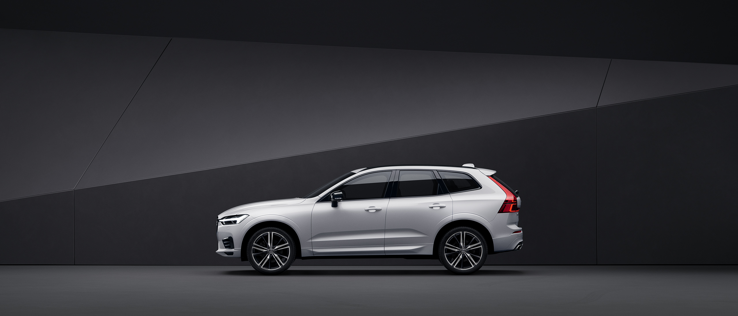 Side view of a silver Volvo XC60 parked in a black indoor environment.