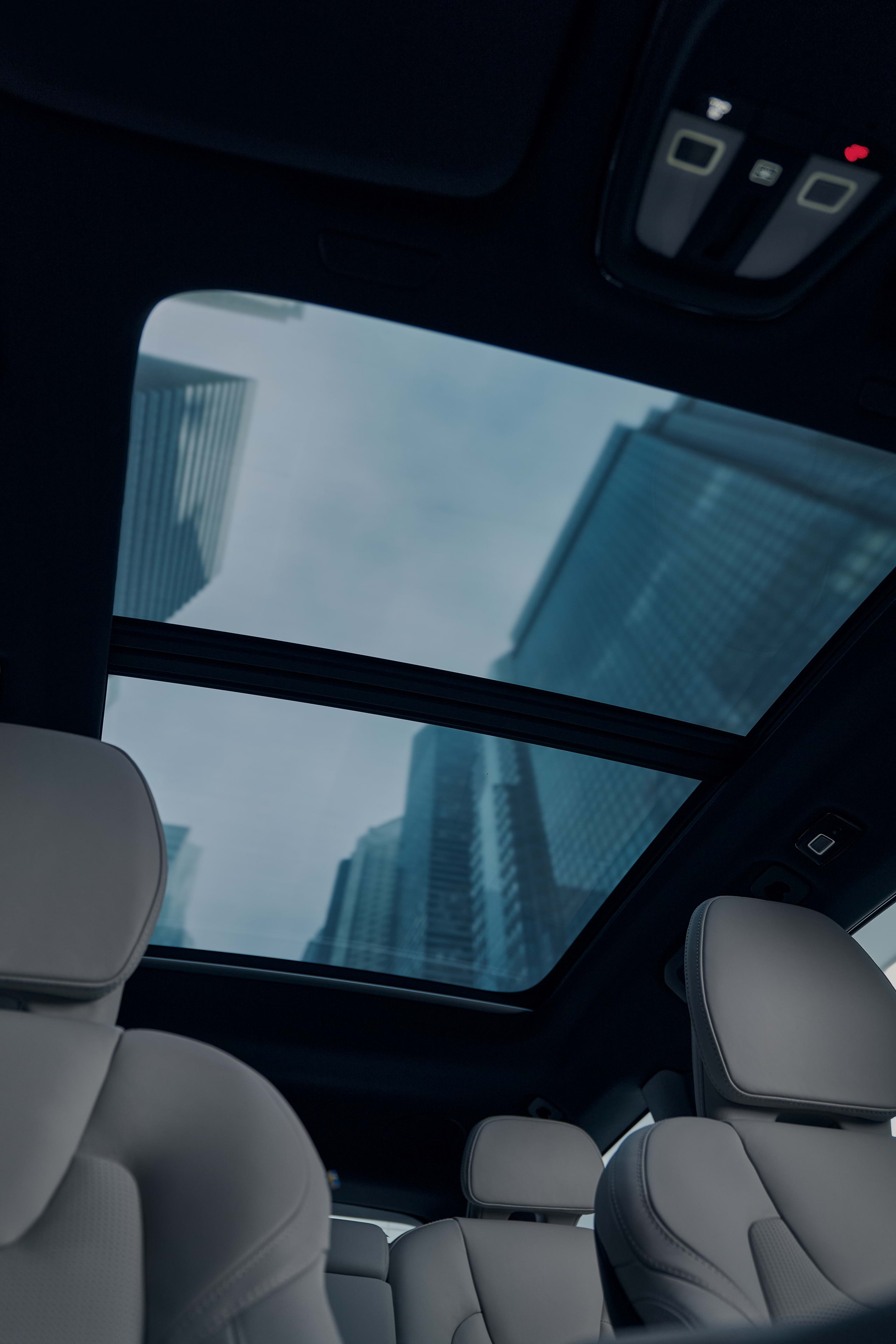 Pro važiuojančio „Volvo“ automobilio panoraminį stoglangį vos matyti dangoraižiai.