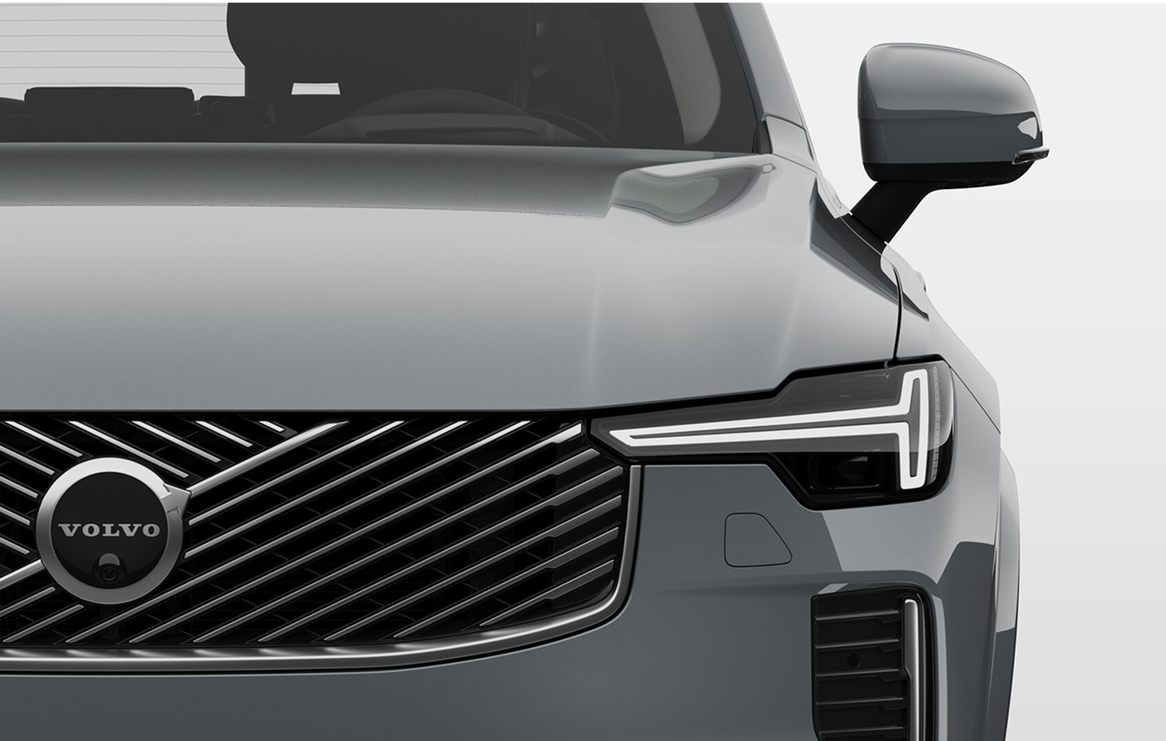 Volvo uzlādējamā hibrīda automašīnas tuvplāns ar
skatu uz tērauda režģa un gludiem priekšējiem lukturiem.