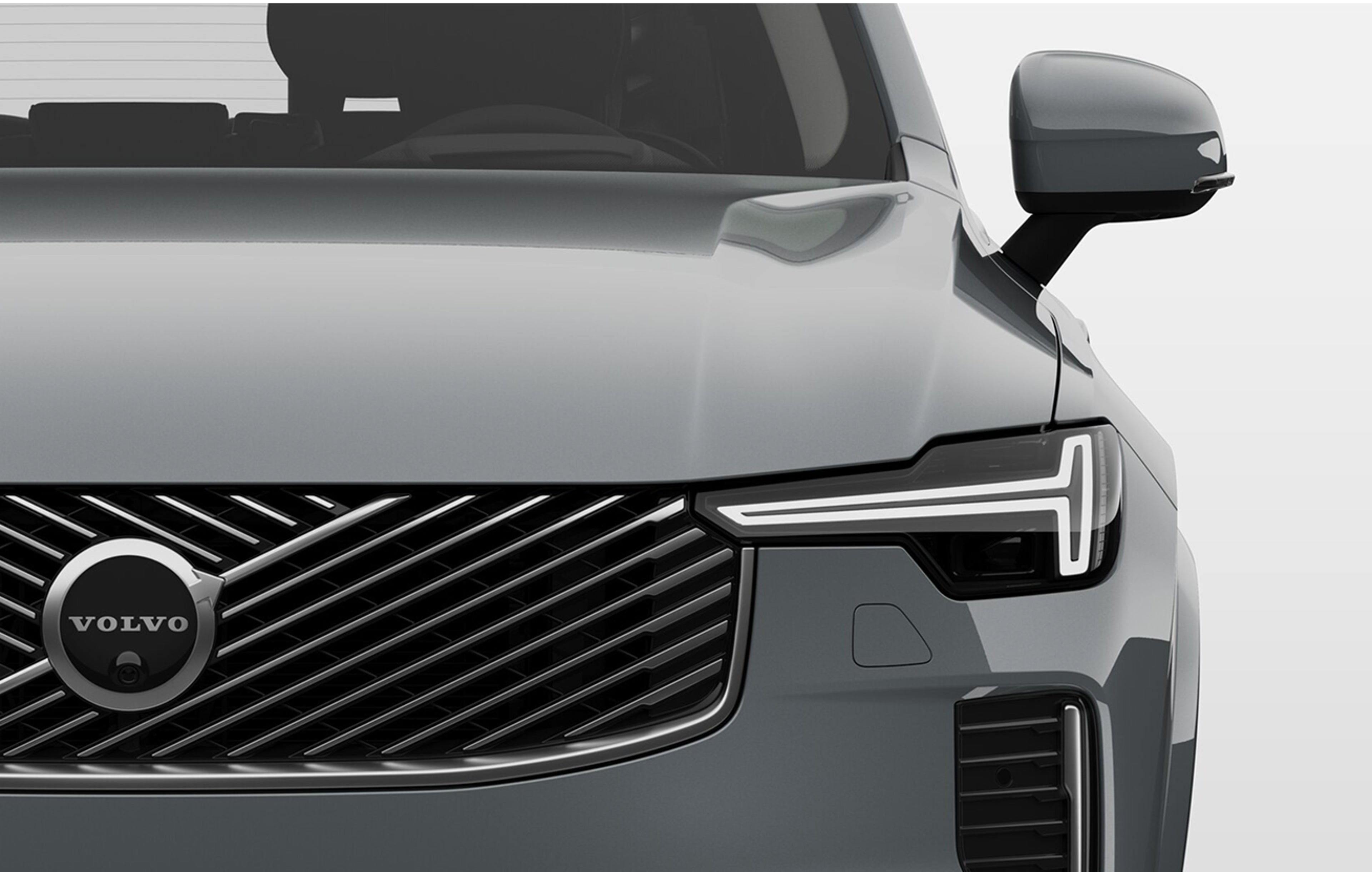 Vue avant rapprochée d’une Volvo plug-in hybride avec un gros plan sur la calandre en acier et les phares élégants.