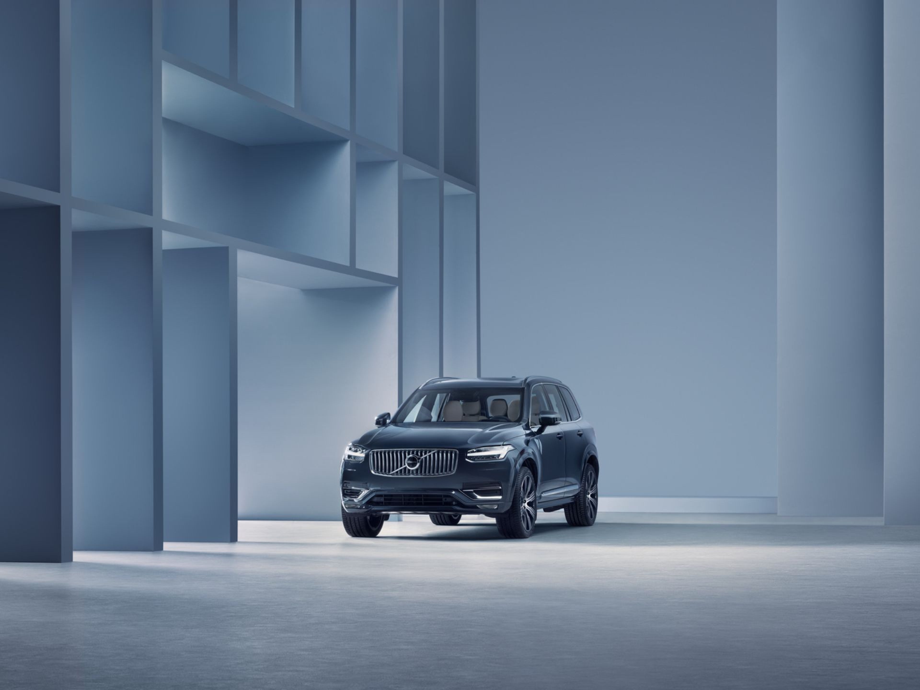 Vue arrière d'un Volvo EX90 électrique sur la plage avec un homme, un chien et deux enfants courant vers l'océan.