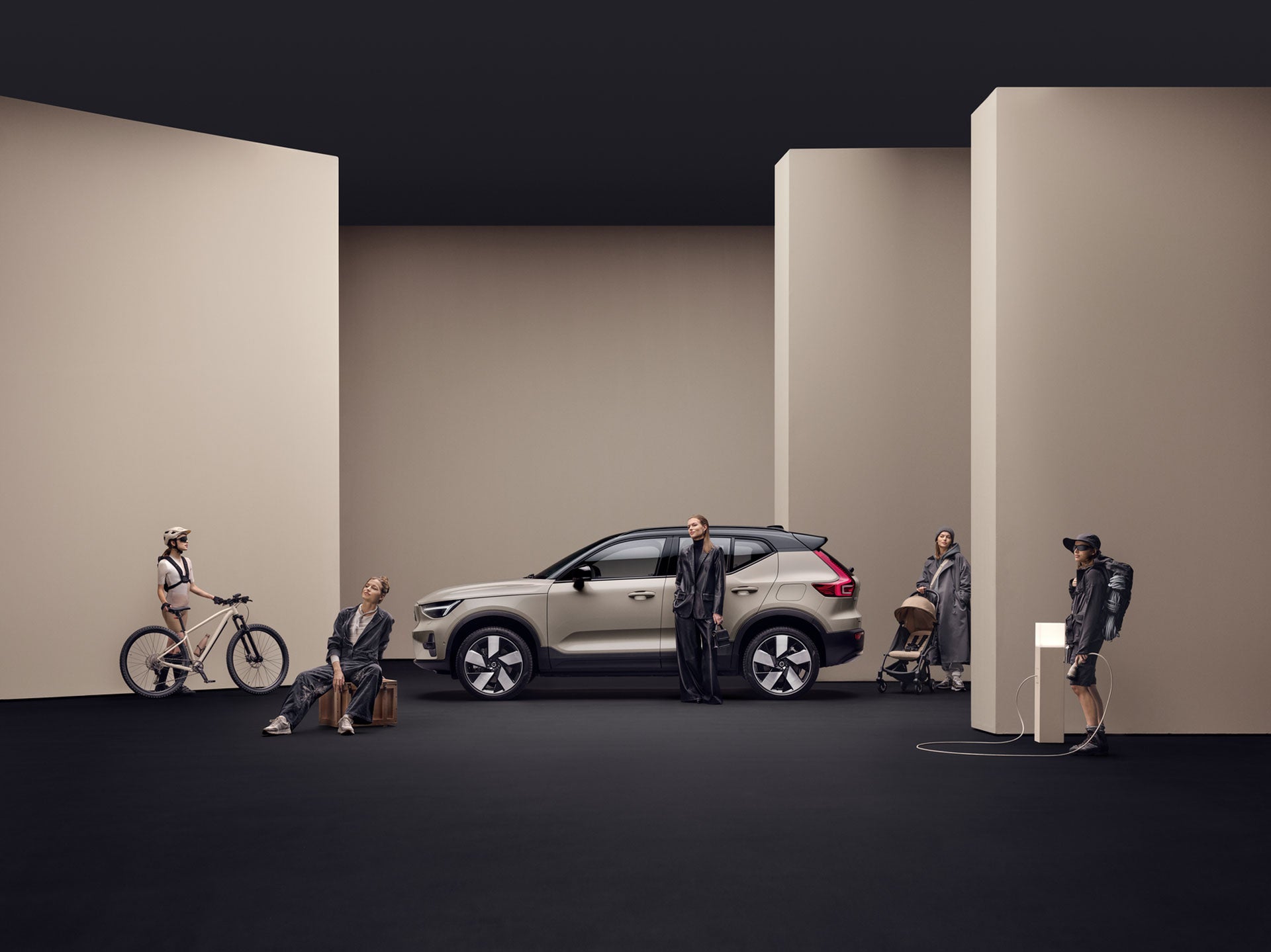 A sage green Volvo EX40 with an open tailgate and suitcases inside.