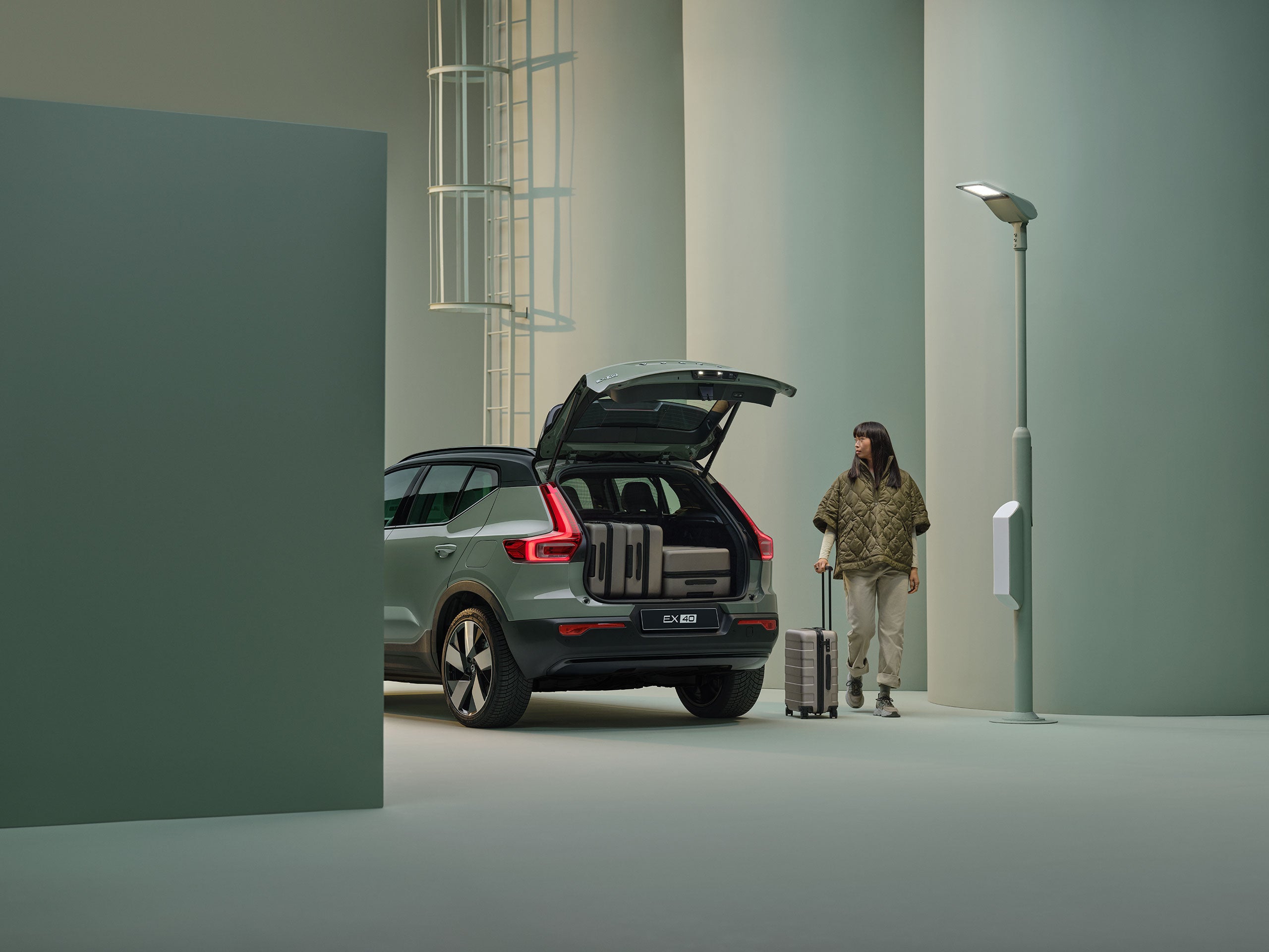 Volvo EX40 Vert Sauge avec le hayon ouvert et des valises à l'intérieur.